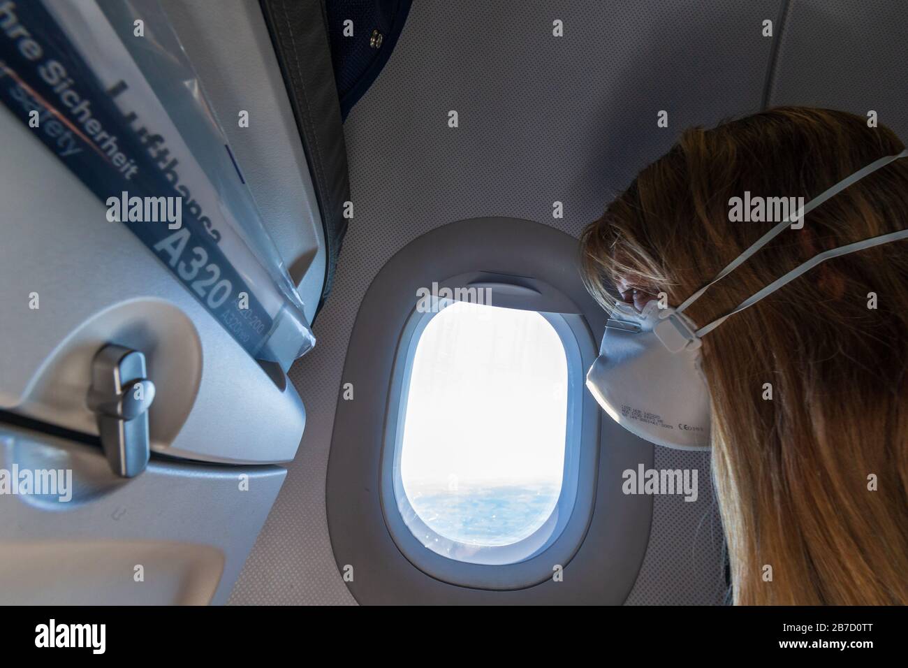 Europa - 15. März 2020: Frau in einem Flugzeug mit Gesichtsmaske zum Schutz vor dem sars-cov-2-Virus Stockfoto