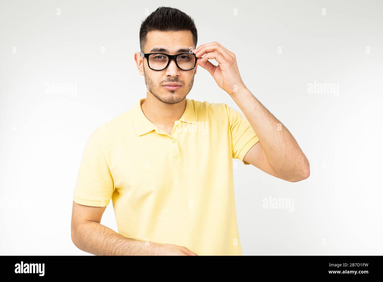 Der Mann stellt sich auf einen weißen Hintergrund eine Brille für die Sehkraft Stockfoto