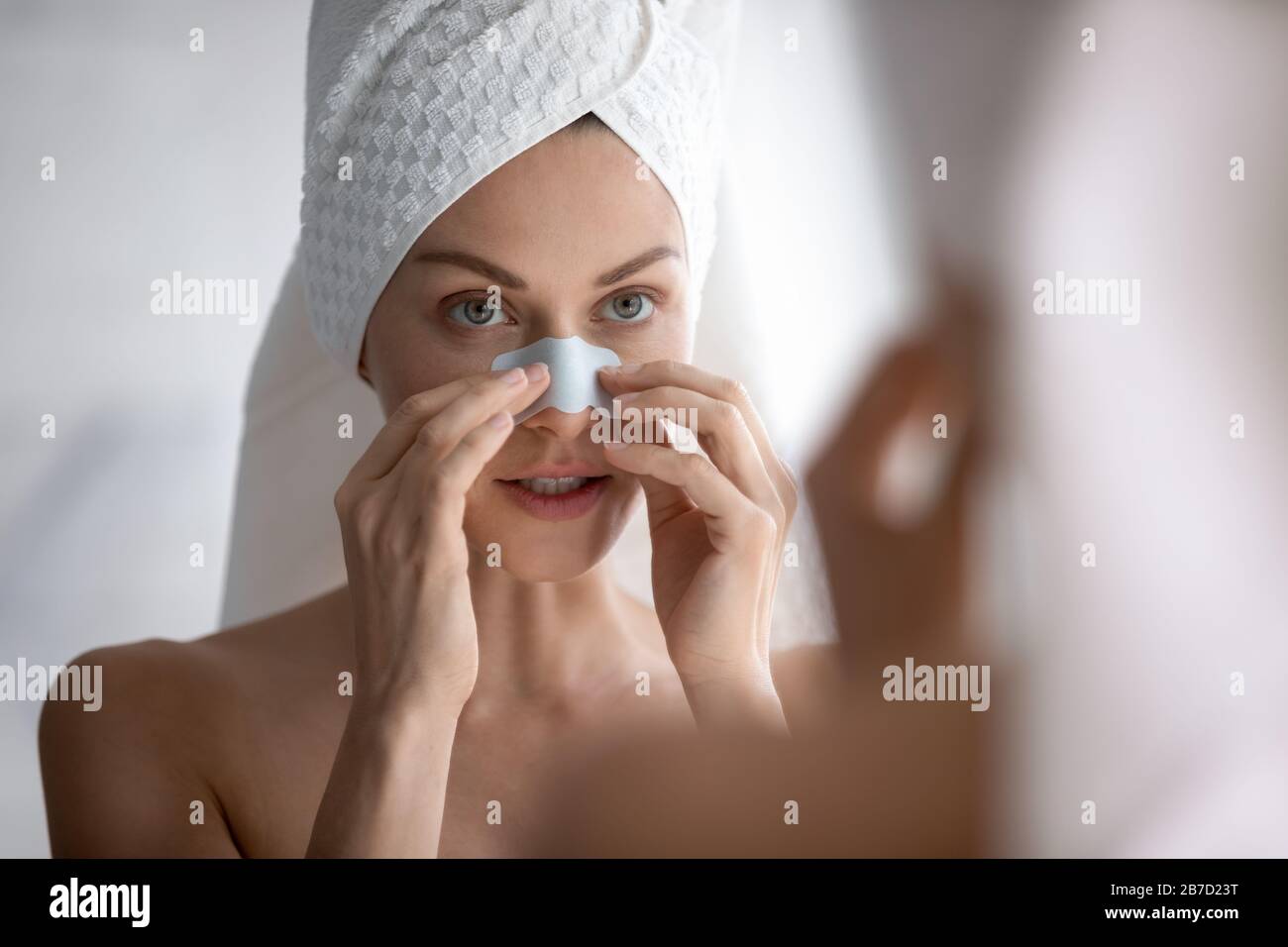 Junge schöne Frau, die Reinigungsstreifen anwendet und dunkle Flecken entfernt. Stockfoto