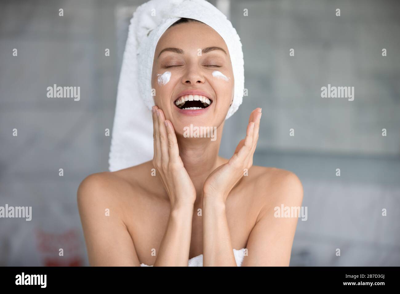 Fröhliche Dame, die allein im Bad professionelle Hautpflegeprodukte verwendet. Stockfoto