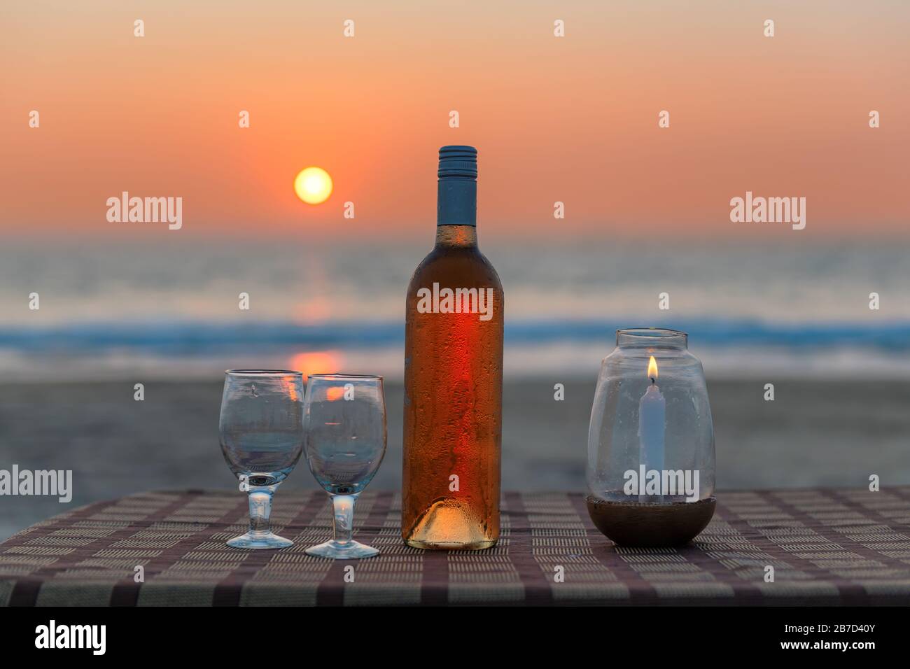Blick auf den Sonnenuntergang auf die Strandparty im Strandcafé mit einer Flasche Rosengwein und Gläsern auf dem Tisch, GOA, Indien. Stockfoto