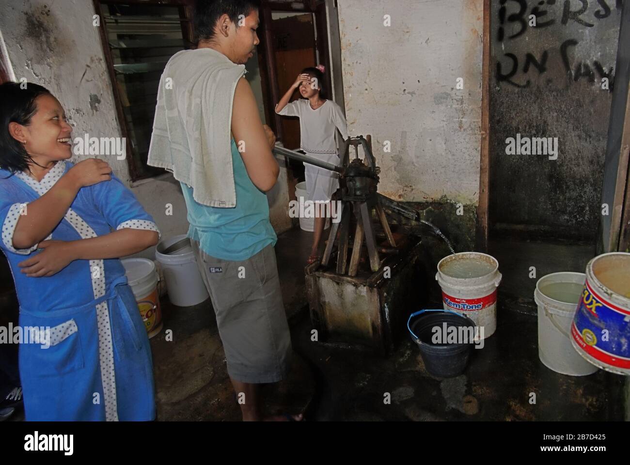 Die lokale Gemeinde nutzt eine kommunale Grundwasserpumpe in einem dichten Stadtviertel in Jakarta, Indonesien. Stockfoto