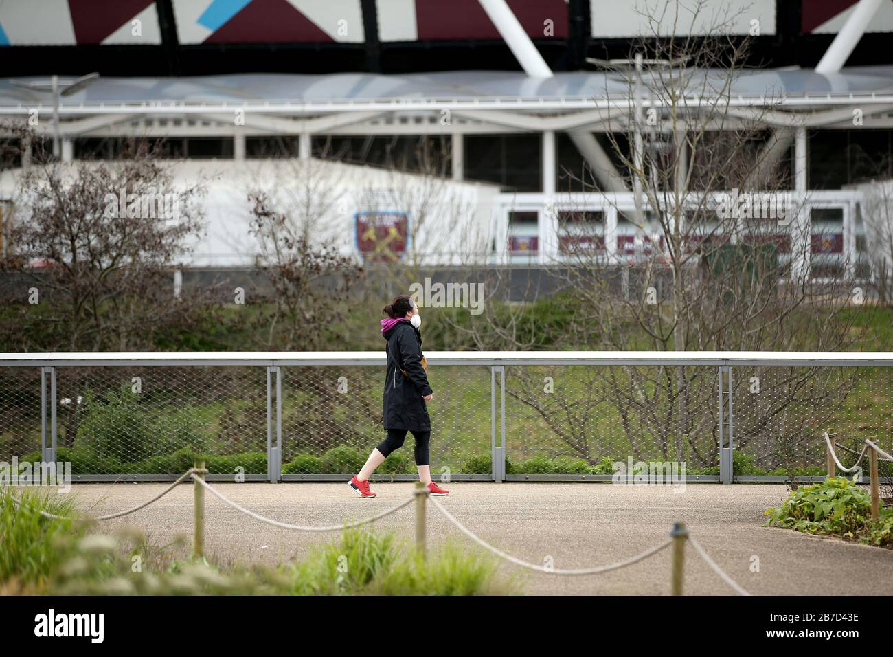 Eine Person, die eine Gesichtsschutzmaske trägt, wird in der Nähe des Londoner Stadions, der Heimat des West Ham United Football Club, gesehen, nachdem am Freitag bekannt gegeben wurde, dass die Premier League alle Spiele bis Samstag, den 4. April 2020 ausgesetzt hat. Stockfoto
