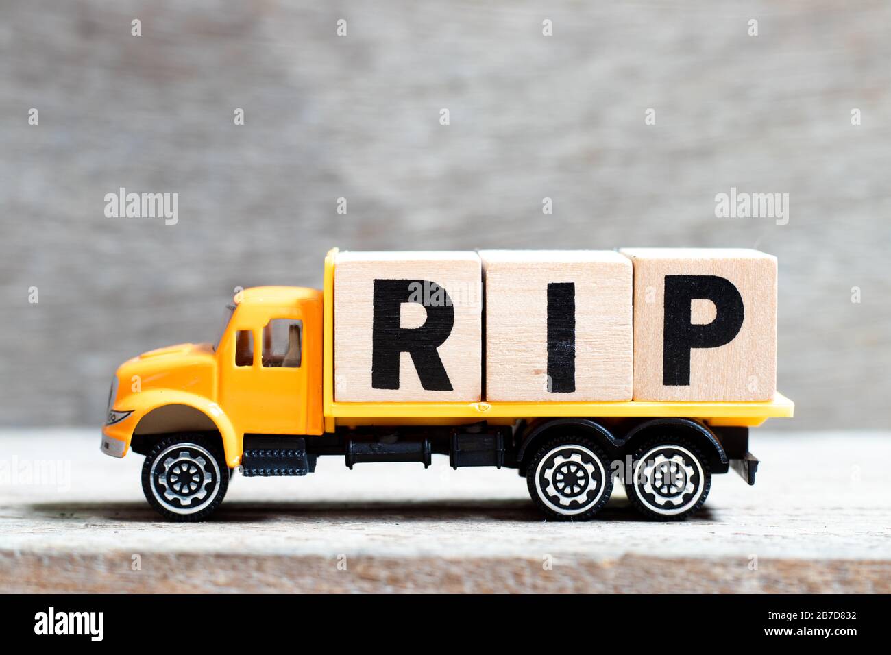 LKW hält Buchstabenblock im Wort RIP (Abkürzung für Rest in Ruhe) auf Holzhintergrund Stockfoto
