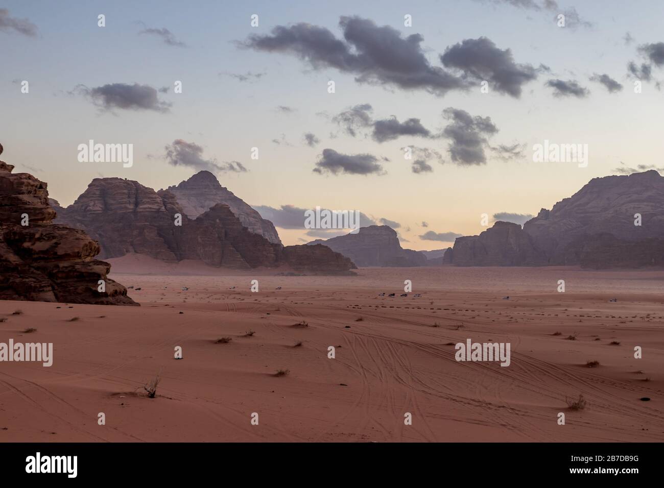 Königreich Jordanien, Wadi Rum Wüste, Sonnenuntergang Winter Tag Landschaft mit weißen geschwollenen Wolken und warmen Farben. Schöne Reisefotografie. Wunderschöne Wüste kann auf Safari erkundet werden. Farbenfrohe Bilder Stockfoto