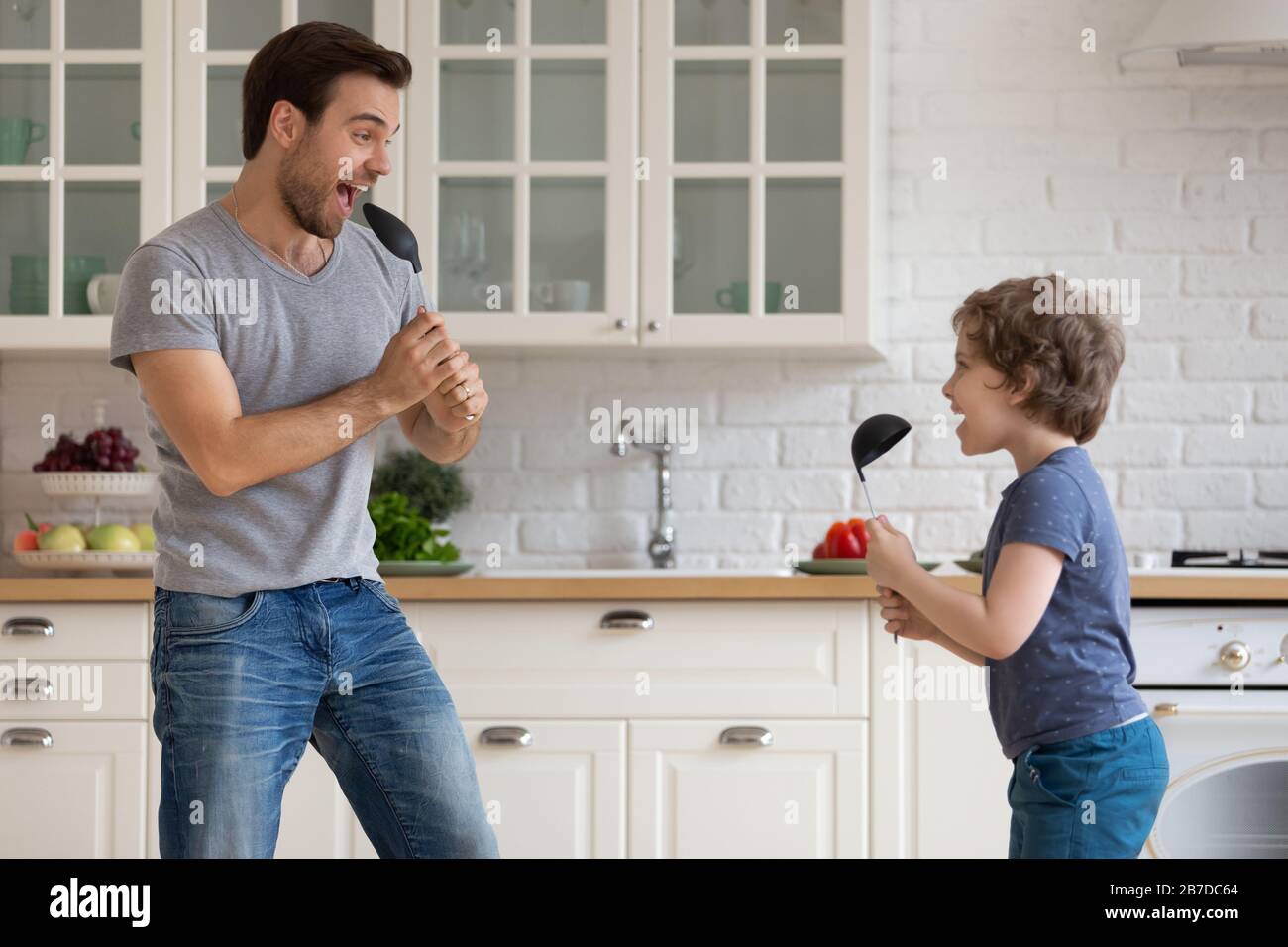 Glücklicher Vater und kleiner Sohn haben Spaß zu Hause zu singen Stockfoto