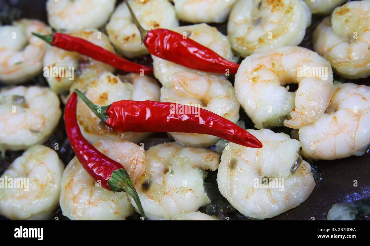 Nahaufnahme von gebratenen, würzigen, frischen Tigergarnelen in Wok Pfanne mit glänzender roter Chilis Stockfoto