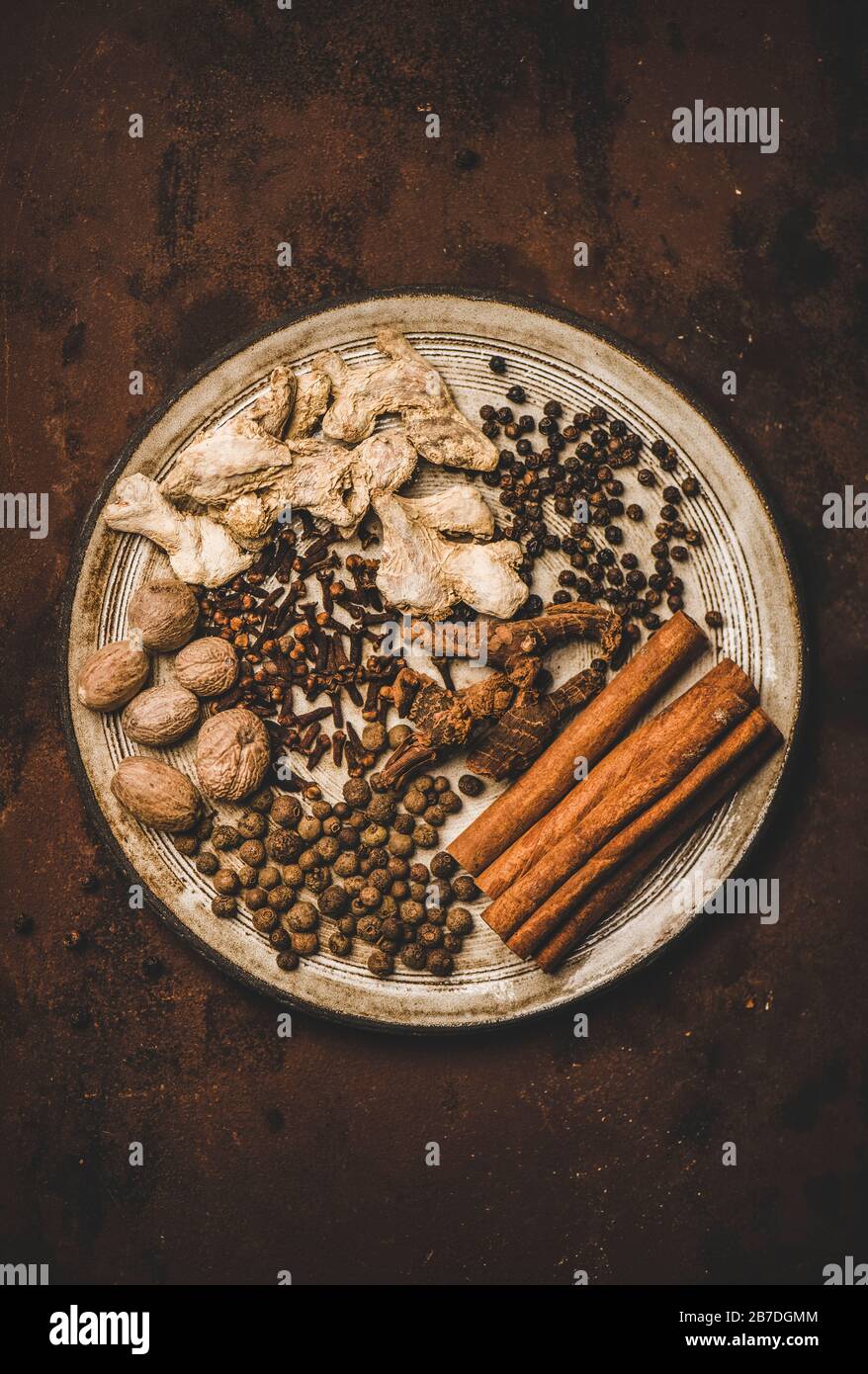 Türkischer traditioneller Seven Spice Yedi Bahar Mix zum Kochen. Flat-lay aus schwarzem Pfeffer, Ingwer, Nelken, Muskatnuss, Zimt, Allwürze und alpinienwurzel in w Stockfoto