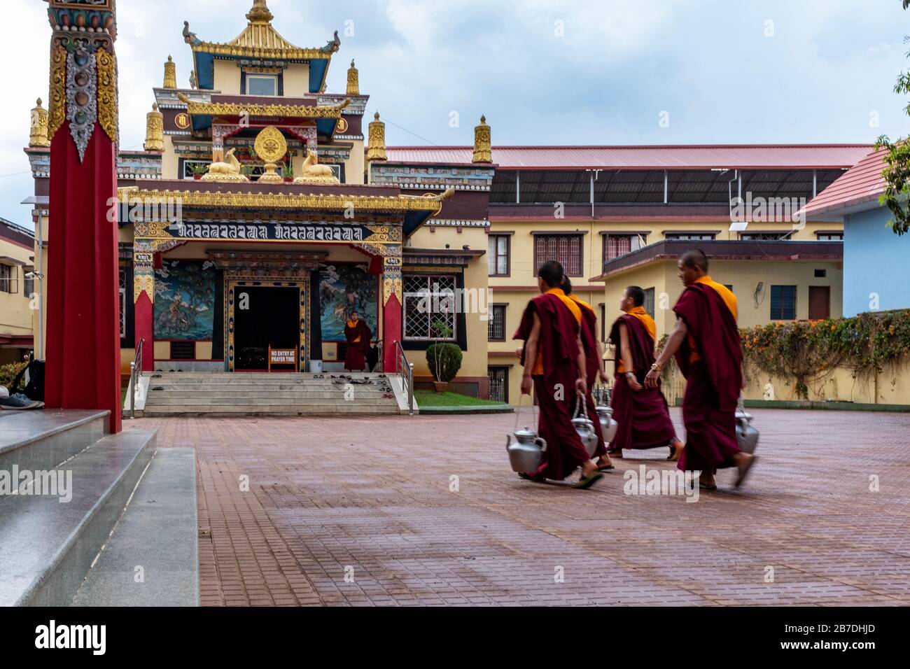 Bylakuppe, Karnataka, Indien - 15. März 2018: Eine Gruppe junger Mönch, die im tibetischen Kloster Namdroling Tee mit einem Tempel im Hintergrund bringt Stockfoto