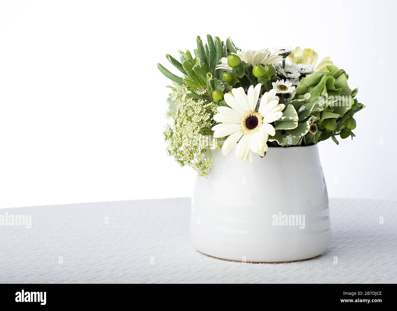 Weiße Tischdecke und weiße china-vase setzen das Grün und weiße Blumenblätter im Blumenzentrum mit Platz für Text ab Stockfoto