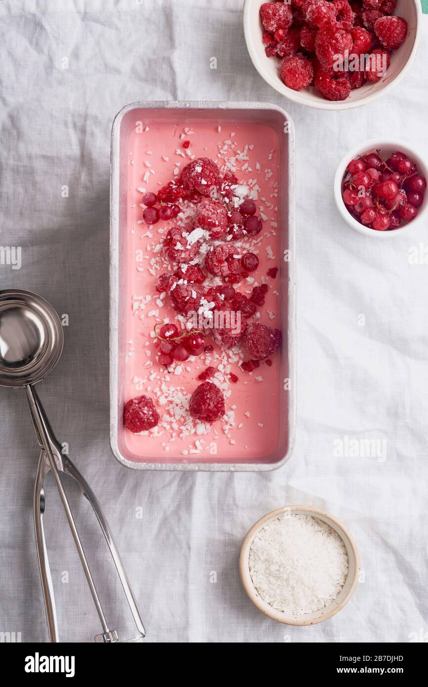 Rosa Eiscreme mit Himbeeren und roten Korinten auf weißem Leinentisch. Overhead-Ansicht Stockfoto