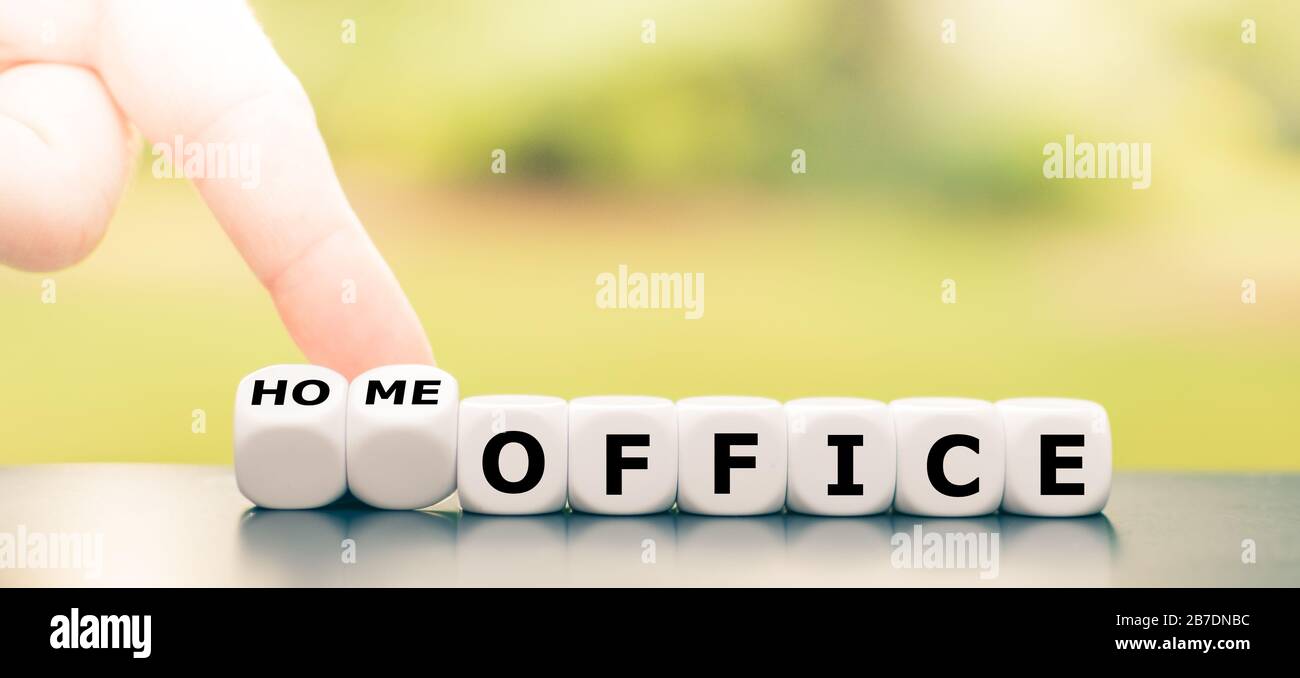 Seien Sie während der Corona-Krise im Büro. Hand dreht Würfel und ändert den Ausdruck "Büro" in "Heimbüro". Stockfoto