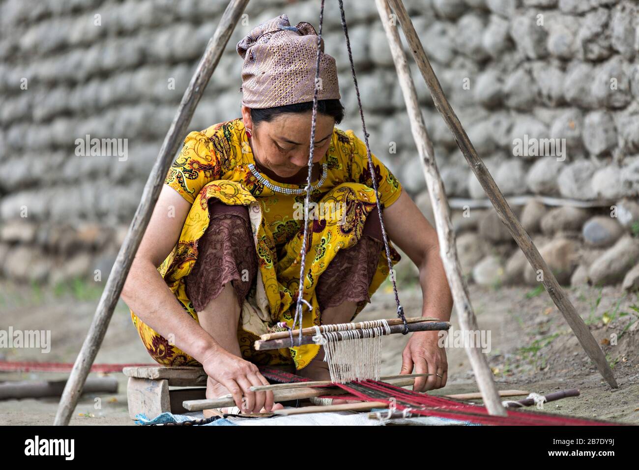 Usbekische Frau in traditioneller Kleiderweberei mit einem alten Webstuhl, in Rishtan, Usbekistan. Stockfoto