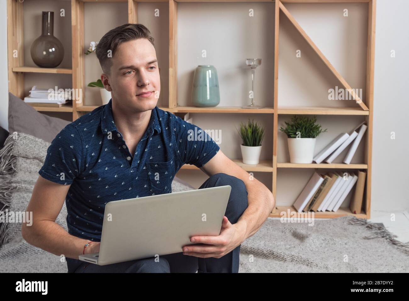 Junger glücklicher Mann, der mit Laptop arbeitet Stockfoto