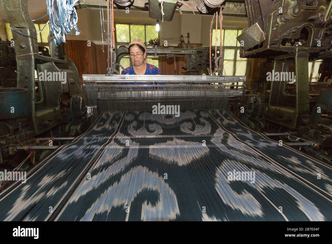 Frau arbeitet und webt Seidenstoff in der Seidenfabrik in Margilan, Usbekistan. Stockfoto