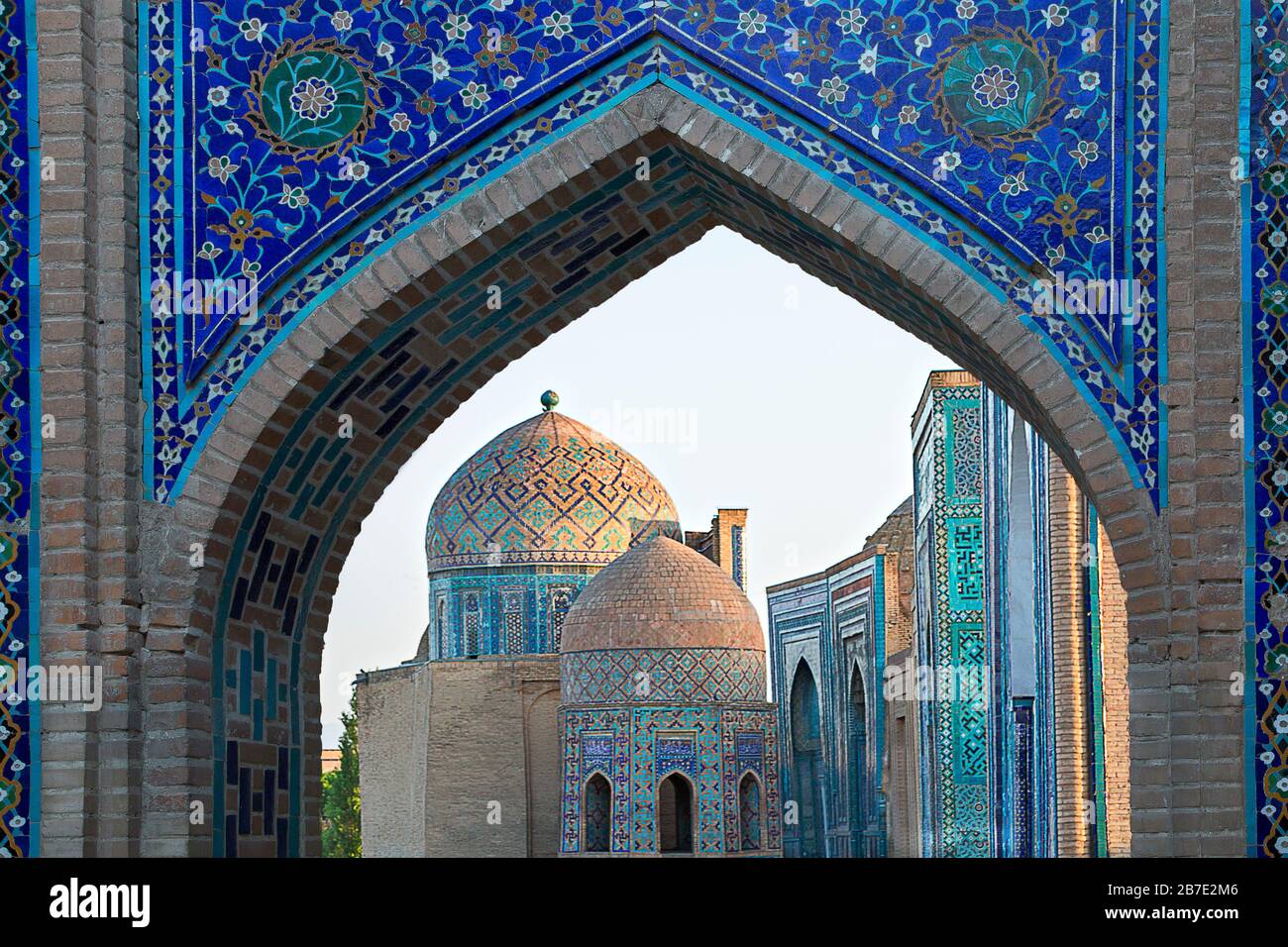 Blick über die Mausoleen und Kuppeln des historischen Friedhofs von Shahi Zinda durch ein bogenförmiges Tor, Samarkand, Usbekistan Stockfoto