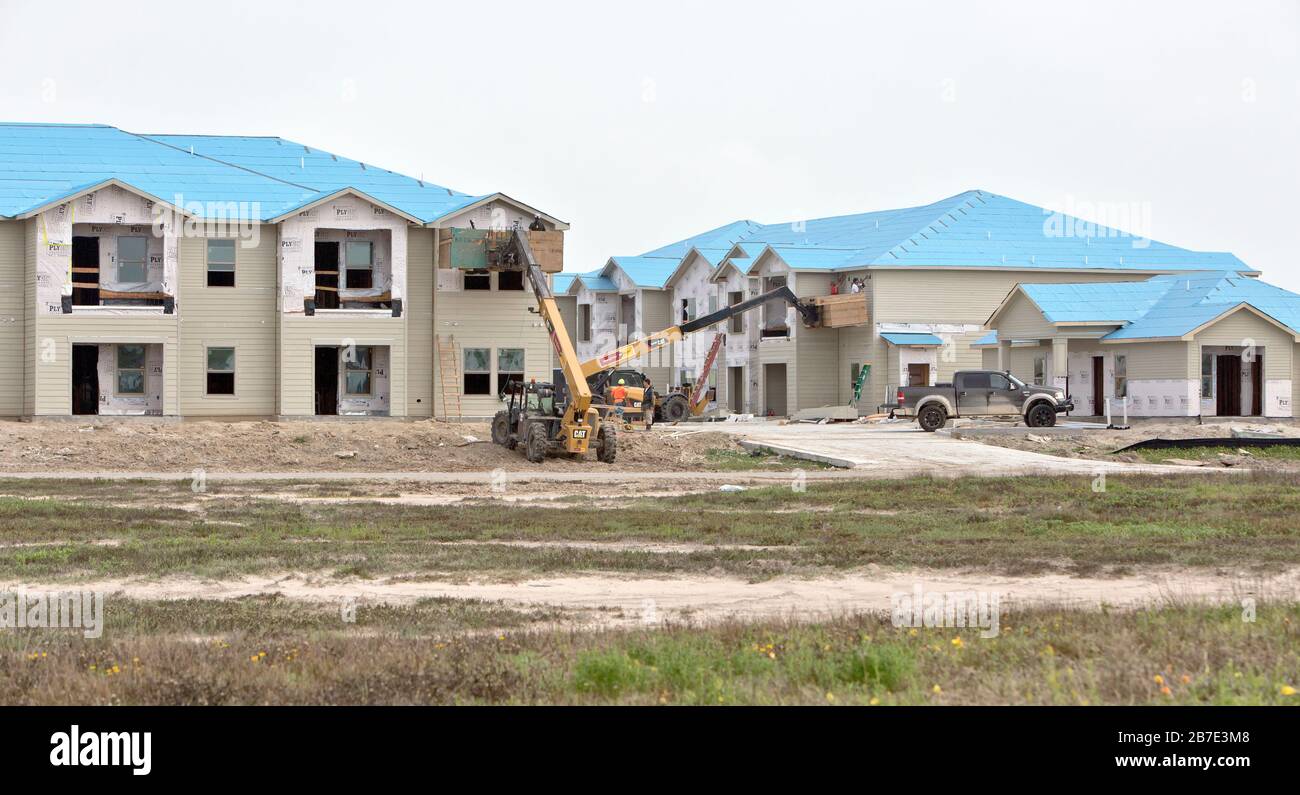 Wiederaufbau Der Salt Grass Landing Apartments. Arbeiter, die die Fensterverkleidung anbringen, mit Caterpillar Materialheber erhöht. Stockfoto