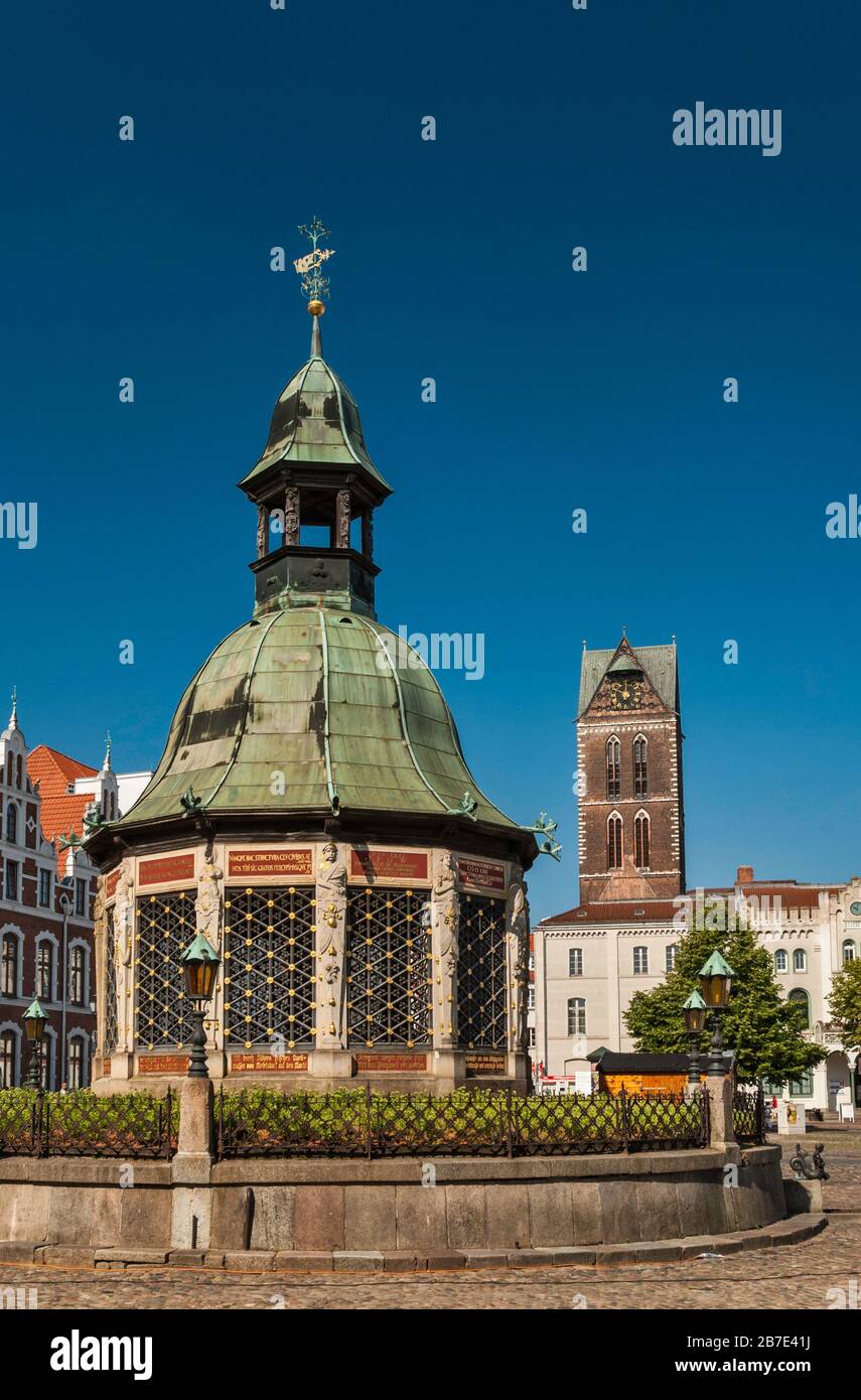 Stadtbrunnen am Marktplatz mit Maria-Turm in der Ferne in Wismar, Mecklenburg-Vorpommern, Deutschland Stockfoto