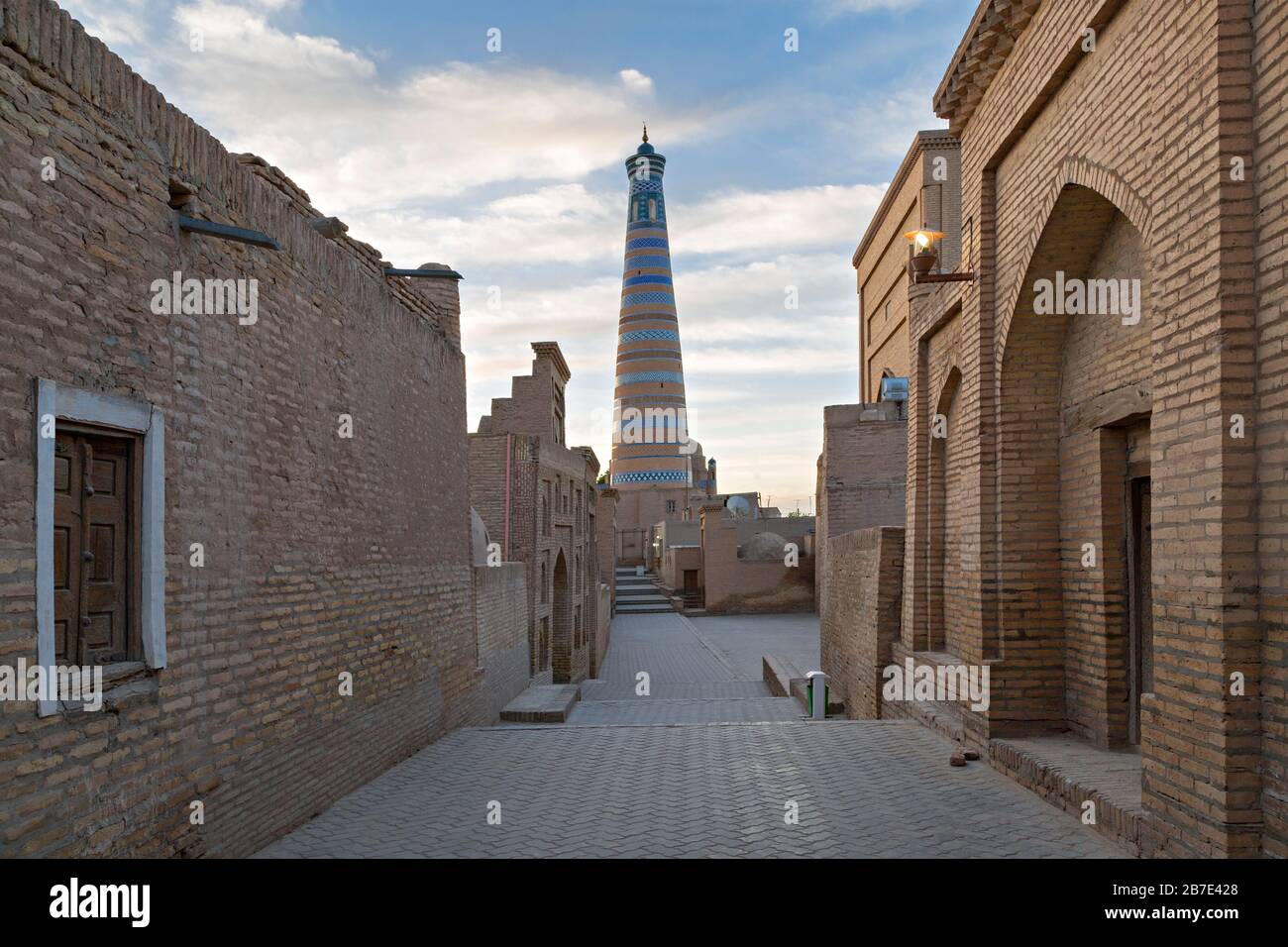 Blick über eine enge Straße mit Minarett im Hintergrund in der antiken Stadt Khiva in Usbekistan Stockfoto