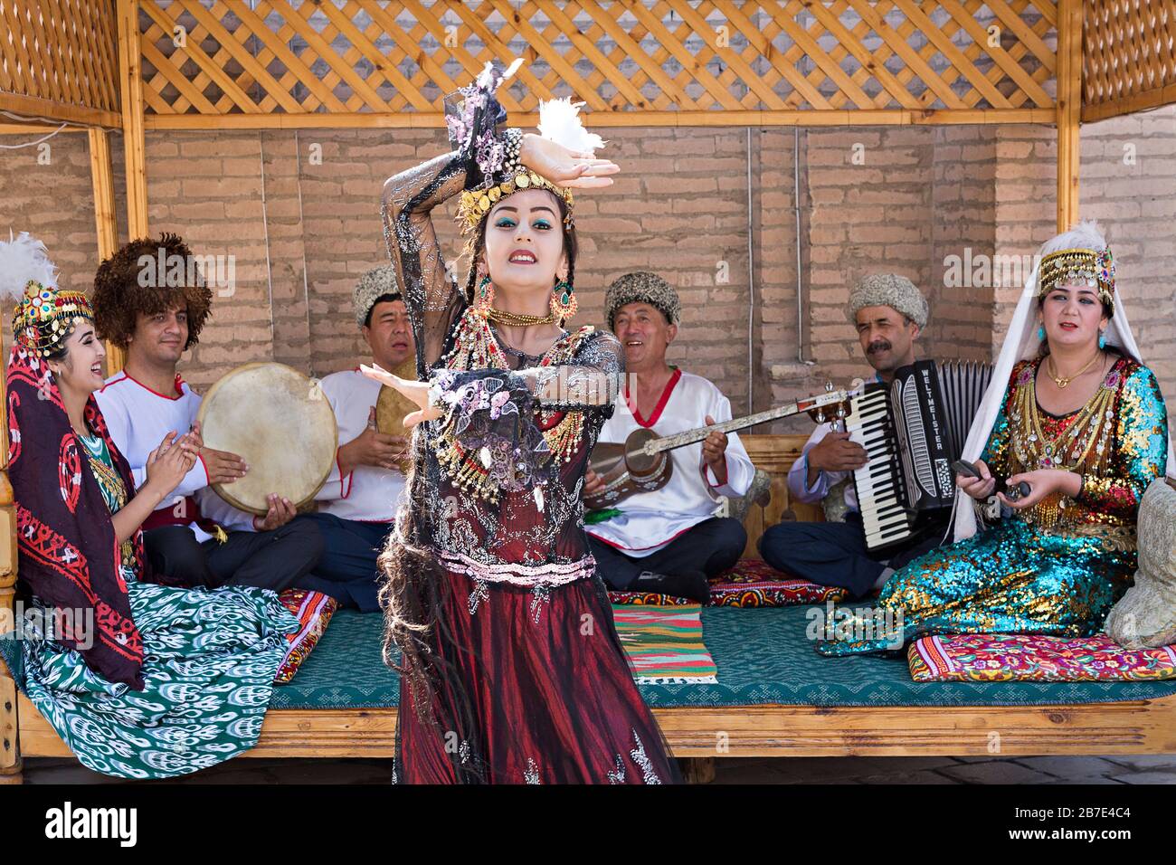 Lokale Musiker spielen und usbekische Frau in traditionellen Kostümen tanzen in Chiwa, Usbekistan Stockfoto
