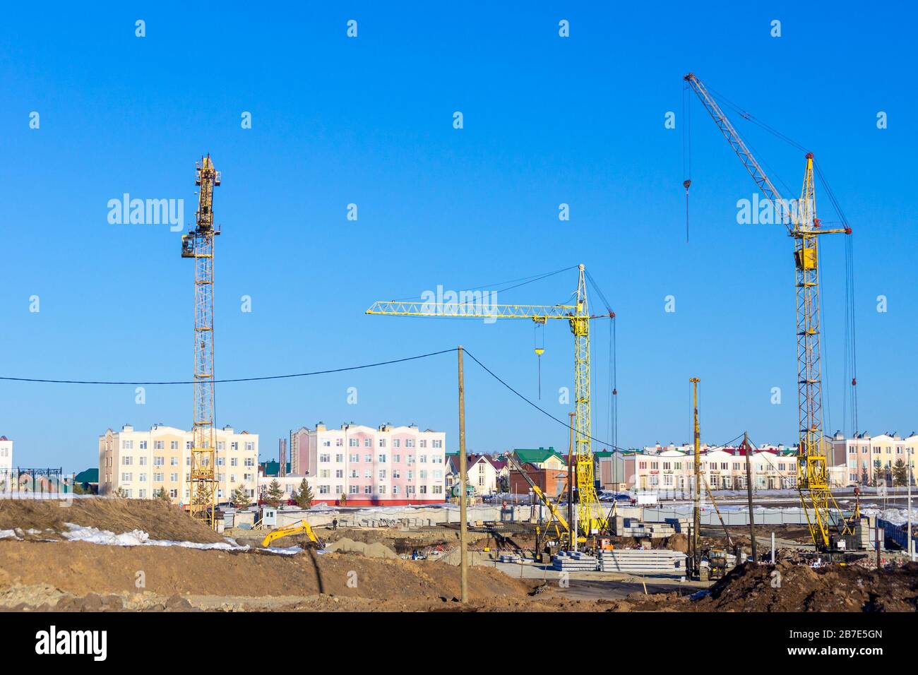 Arbeitsgeräte an der Baustelle. Bagger- und Hubmaschine, Ivanovets LKW-Kran und Turmkräne Stockfoto
