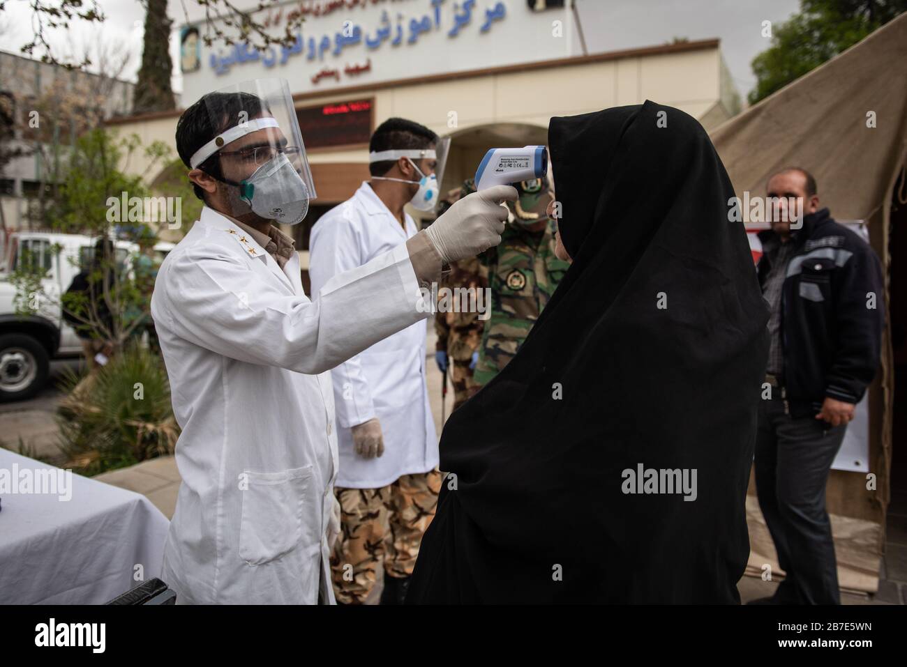 Der Arzt der iranischen Armee überwacht die Körpertemperatur von Menschen auf Straßen, die selbst eine Kontrolle fordern. Die landesweite militärische Zusammenkunft der iranischen Streitkräfte begann mit dem Ziel, das Coronavirus (COVID19) zu bekämpfen und die öffentliche Gesundheit auf Befehl des Obersten Anführers der Islamischen Republik Iran zu verbessern. Provinz Fars, Shiraz. März 2020. Stockfoto