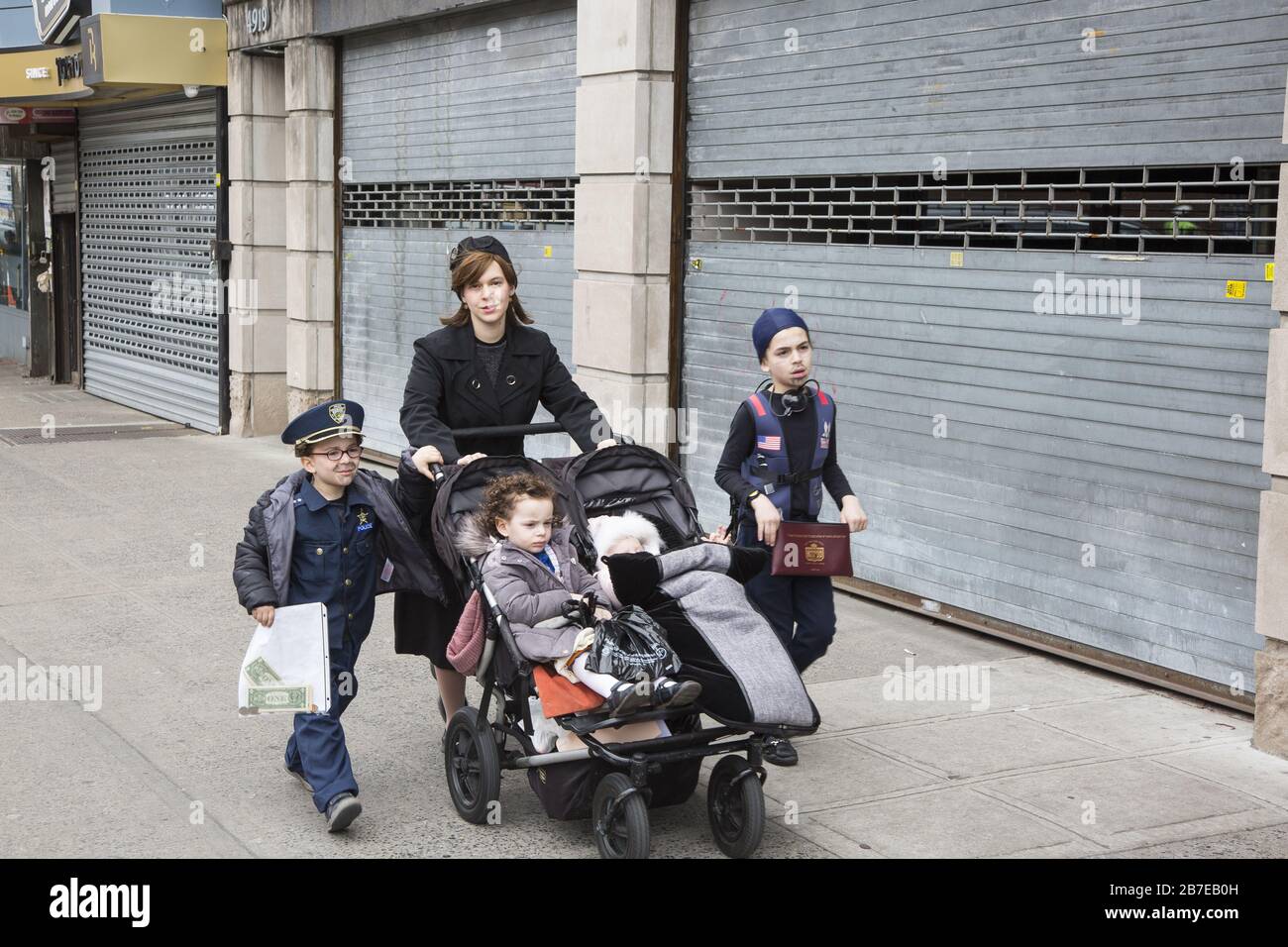 Die orthodoxe jüdische Gemeinde im Borough Park Brooklyn feiert den festlichen Urlaub von Purim, indem sie Kostüme trägt, Armen spendet, leckere Speisen isst und im Allgemeinen eine gute Zeit hat. Die Leute auf der 13th Avenue. Purim wird jedes Jahr am 14. Des hebräischen Monats Adar gefeiert. Es erinnert an die Errettung des jüdischen Volkes im alten Perserreich aus Hamans Handlung "alle Juden, jung und alt, Säuglinge und Frauen, an einem einzigen Tag zu vernichten, zu töten und zu vernichten", wie in der Megillah (Buch Esther) festgehalten. Stockfoto