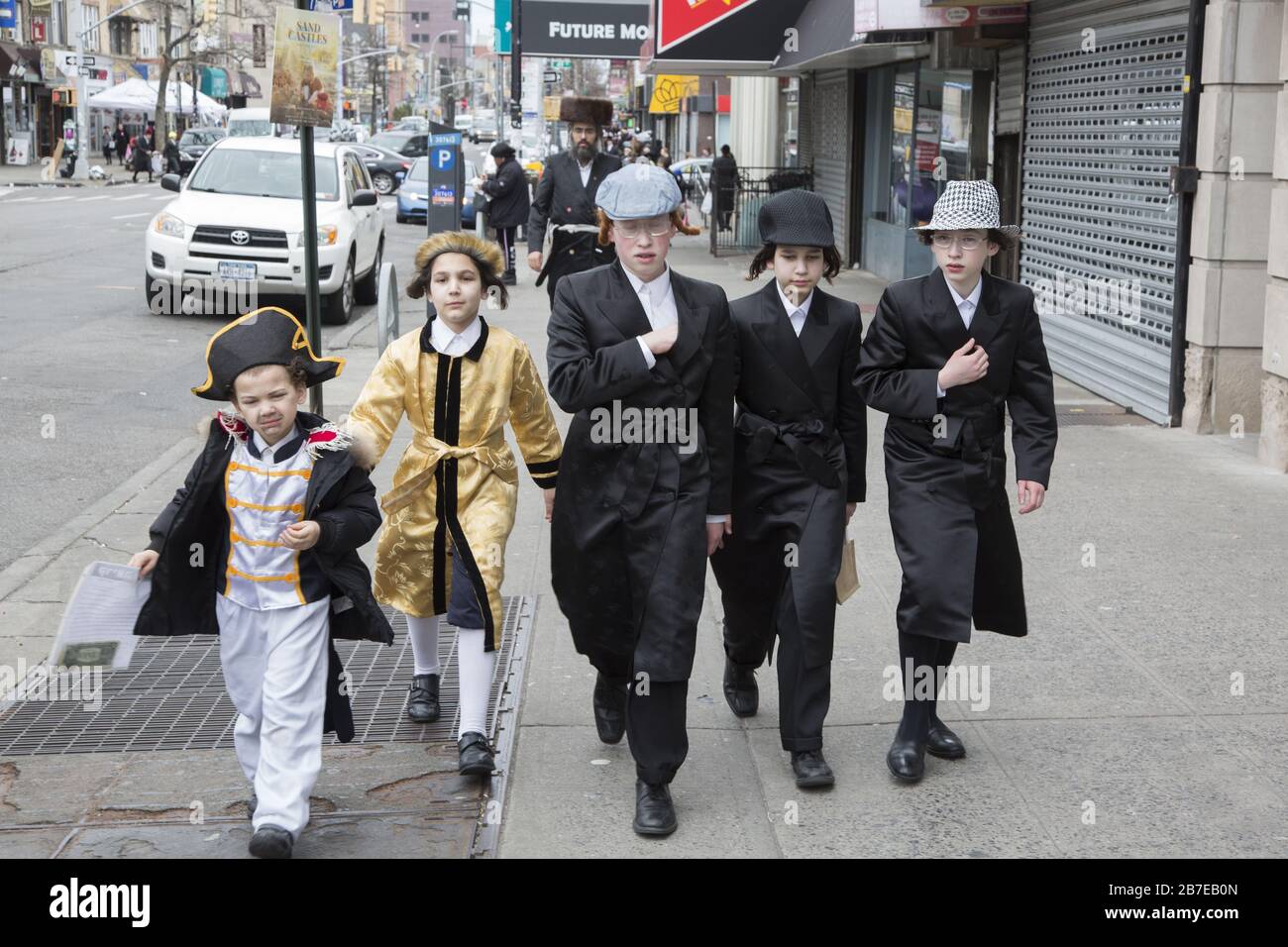 Die orthodoxe jüdische Gemeinde im Borough Park Brooklyn feiert den festlichen Urlaub von Purim, indem sie Kostüme trägt, Armen spendet, leckere Speisen isst und im Allgemeinen eine gute Zeit hat. Die Leute auf der 13th Avenue. Purim wird jedes Jahr am 14. Des hebräischen Monats Adar gefeiert. Es erinnert an die Errettung des jüdischen Volkes im alten Perserreich aus Hamans Handlung "alle Juden, jung und alt, Säuglinge und Frauen, an einem einzigen Tag zu vernichten, zu töten und zu vernichten", wie in der Megillah (Buch Esther) festgehalten. Stockfoto