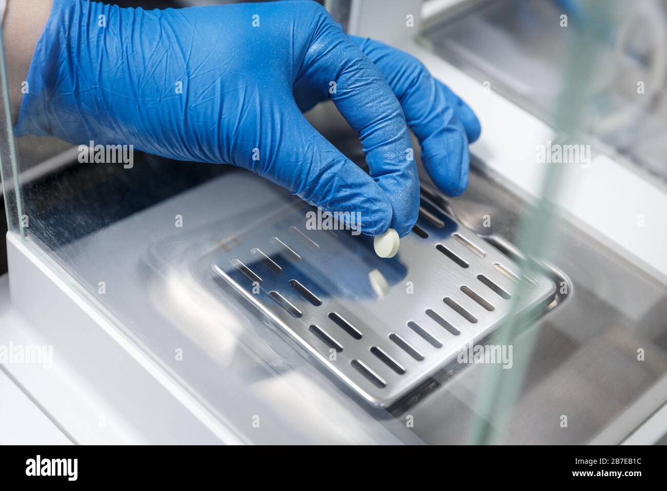 Apotheker in medizinischen Handschuhen, die neue Arzneipille in einem pharmazeutischen Labor wiegen. Konzept der pharmazeutischen Industrie Stockfoto