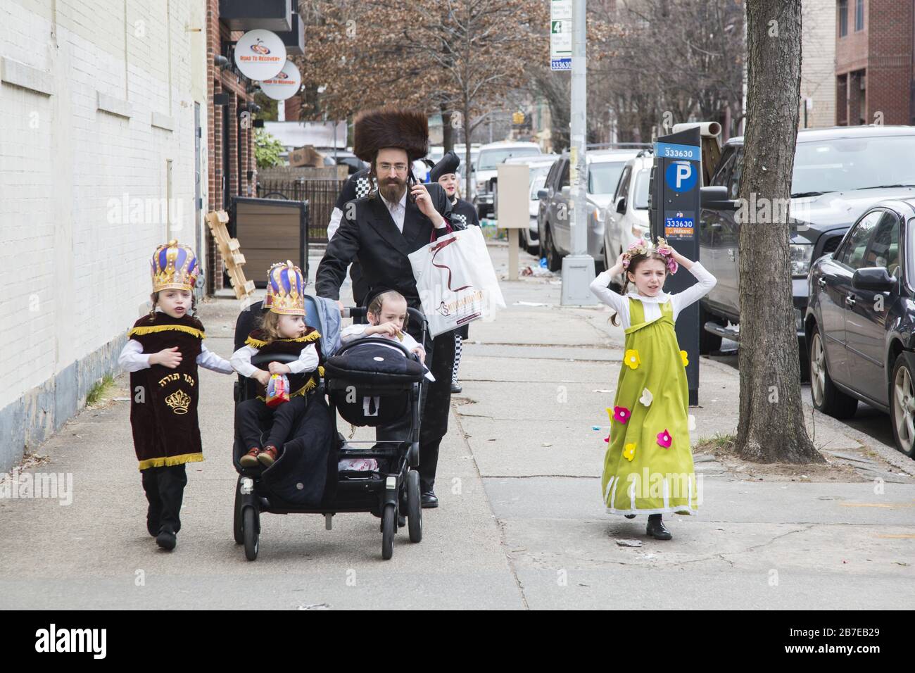Die orthodoxe jüdische Gemeinde im Borough Park Brooklyn feiert den festlichen Urlaub von Purim, indem sie Kostüme trägt, Armen spendet, leckere Speisen isst und im Allgemeinen eine gute Zeit hat. Die Leute auf der 13th Avenue. Purim wird jedes Jahr am 14. Des hebräischen Monats Adar gefeiert. Es erinnert an die Errettung des jüdischen Volkes im alten Perserreich aus Hamans Handlung "alle Juden, jung und alt, Säuglinge und Frauen, an einem einzigen Tag zu vernichten, zu töten und zu vernichten", wie in der Megillah (Buch Esther) festgehalten. Stockfoto