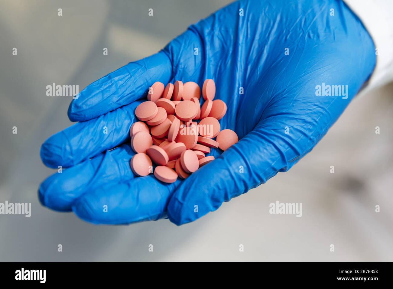 Apotheker in blauen medizinischen Handschuhen, die neu entwickelte Arzneipillen in einem pharmazeutischen Labor halten. Konzept der pharmazeutischen Industrie Stockfoto