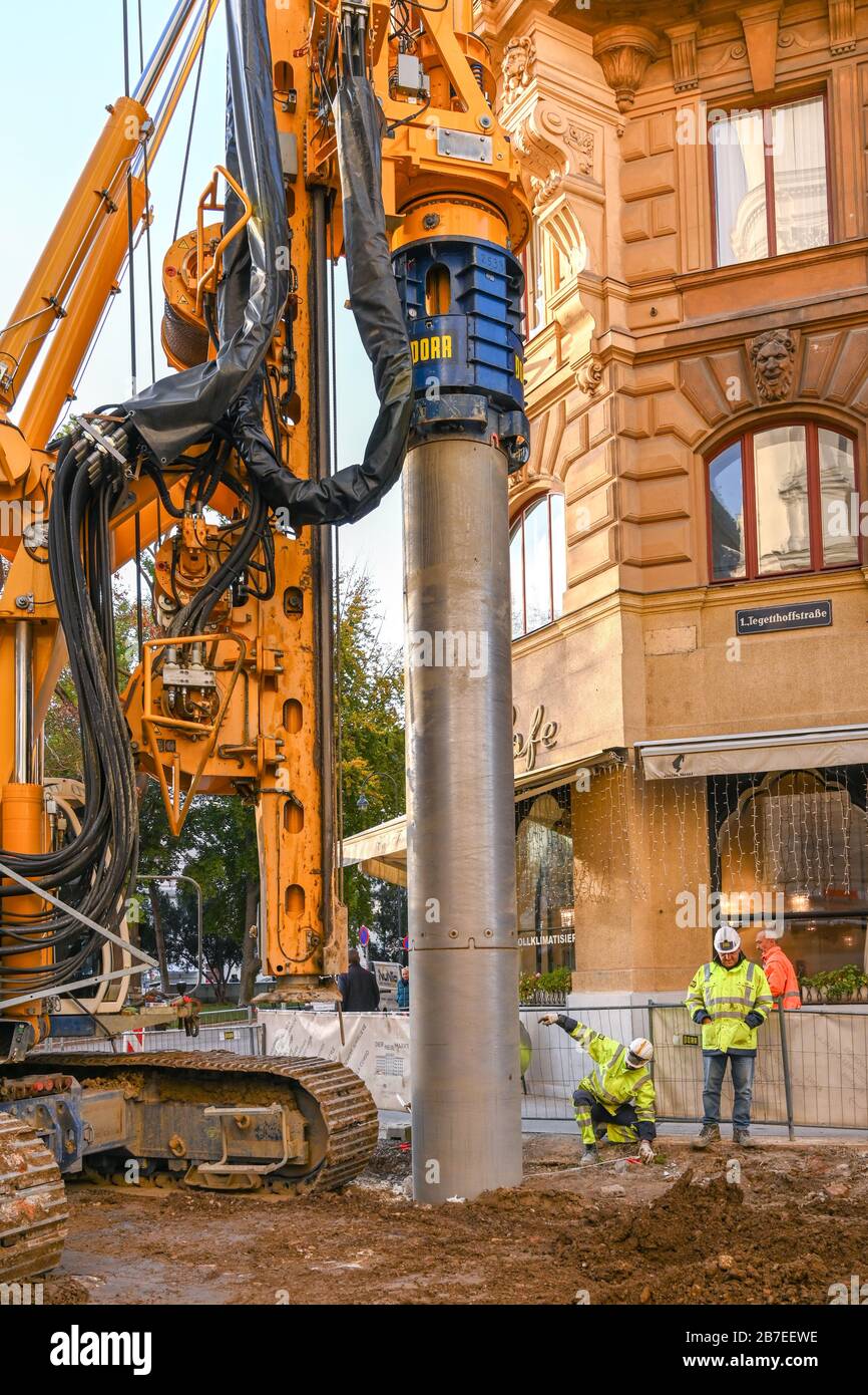 WIEN, ÖSTERREICH - NOVEMBER 2019: Bauarbeiter signalisieren dem Fahrer einer Bohrmaschine, ein Bohrrohr auf einem Gelände in Wien zu positionieren Stockfoto