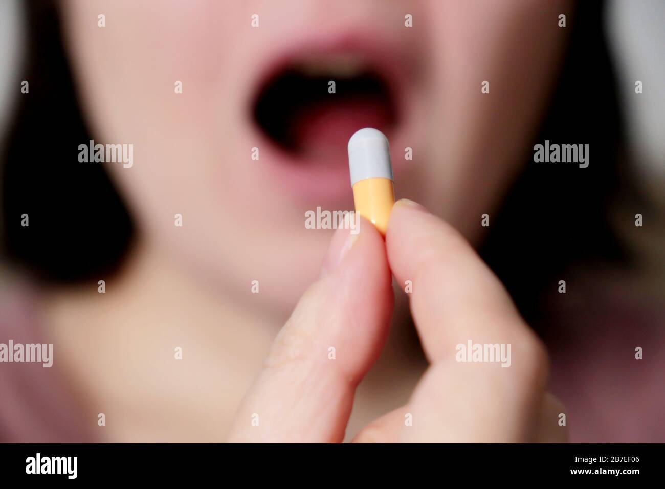 Frau nimmt eine Tablette, Mädchen legt Kapsel in offenen Mund. Kranke Frauen, die Medikamente nehmen, Konzept von Antibiotika, Vitamin, Coronavirus Prävention Stockfoto