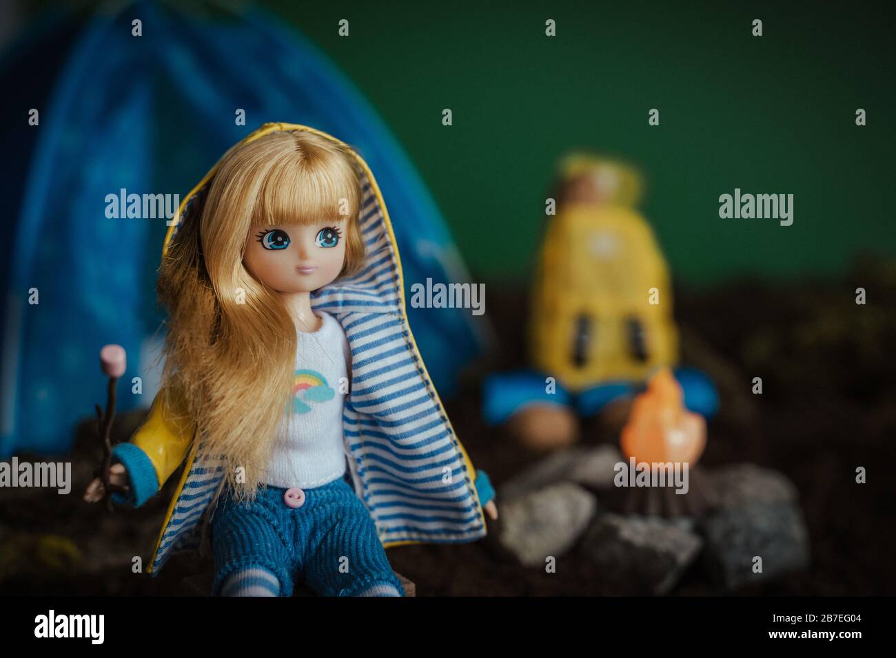 Nahaufnahme einer niedlichen Wanderpuppe mit blonden Haaren Mit einem Toy Bonfire im Hintergrund Stockfoto