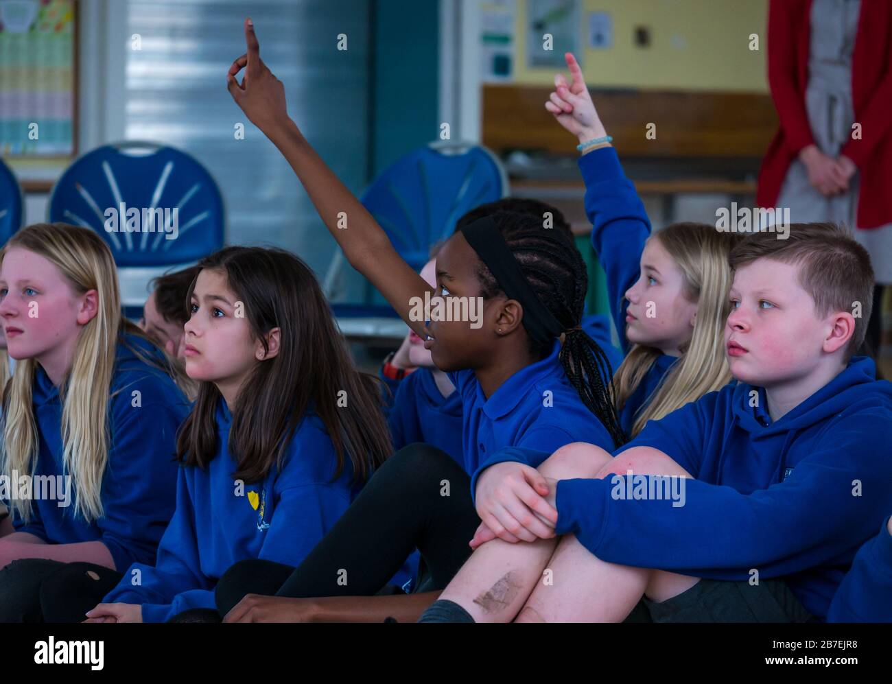 Schulkinder an der Hauptschule von Davidsons Mains mit einem schwarzen Mädchen, das ihre Hand aufhebt, um eine Frage zu beantworten, Edinburgh, Schottland, Großbritannien Stockfoto