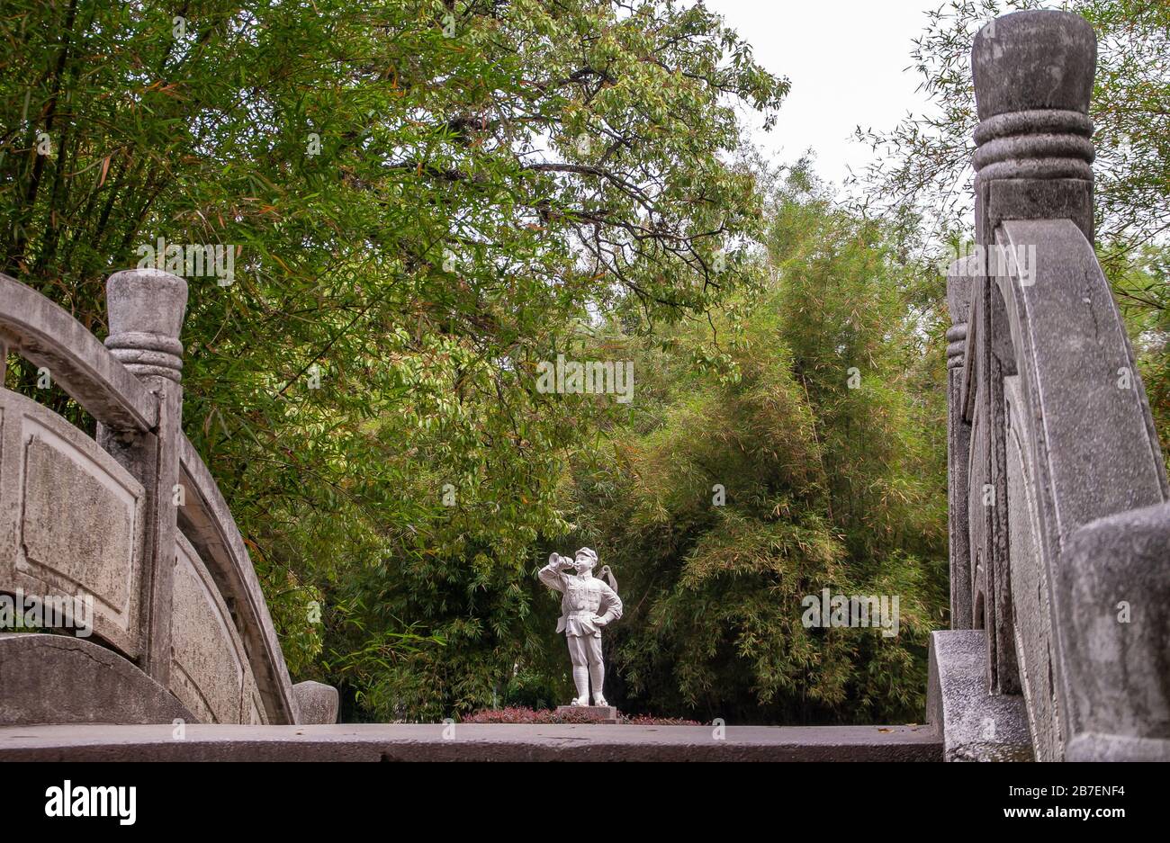 Guilin, China - 11. Mai 2010: Seven Star Park. Weiße Statue des Jungen in Militäruniform, die das Knäuel vor der Wand aus grünem Laub weht, wie es auf fro zu sehen ist Stockfoto