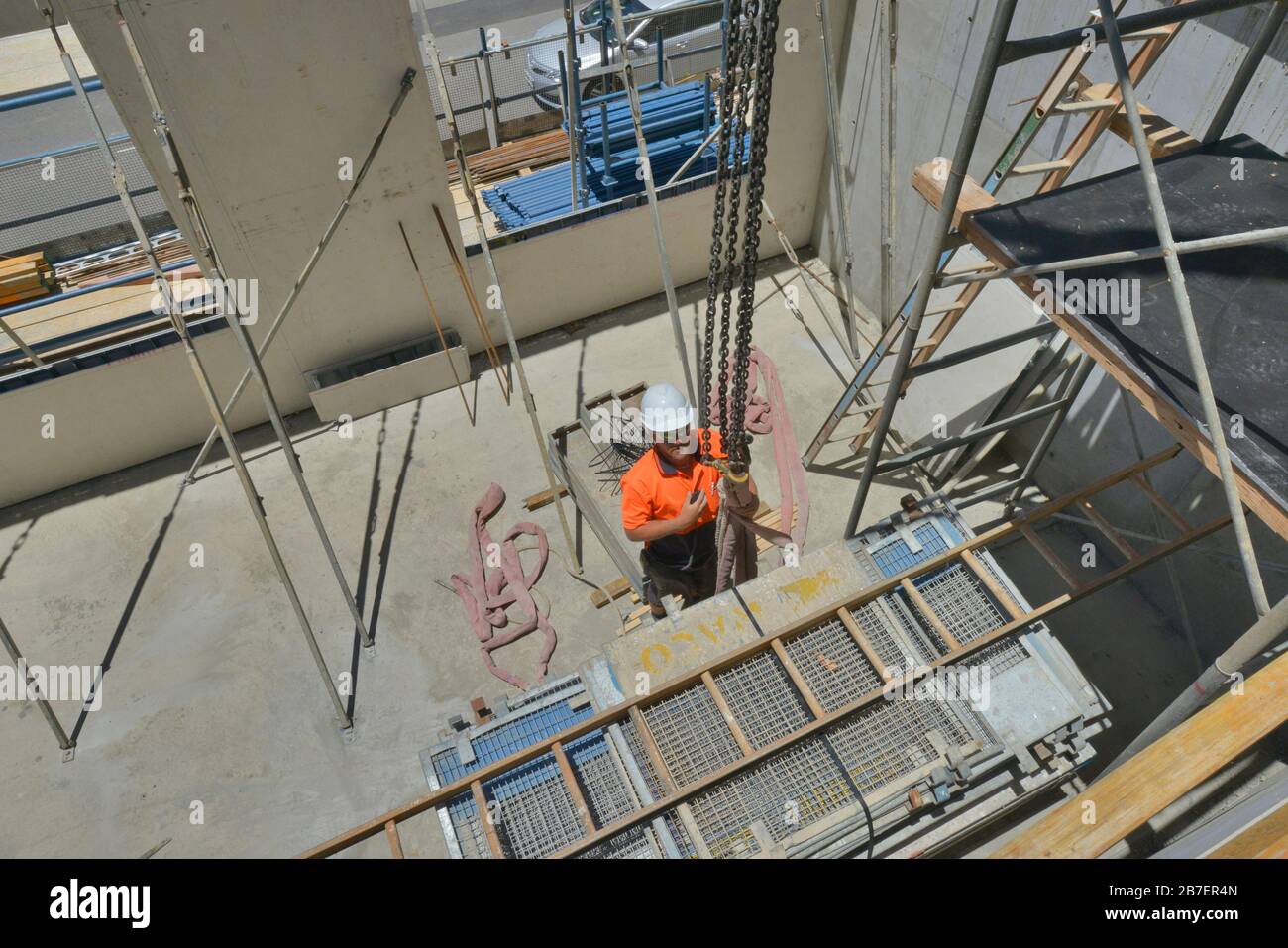 Handwerker bei der Arbeit an einem neuen Architekturprojekt, das Hemd, Stiefel, Helme und Kniepolster mit hoher Sichtbarkeit trägt. Stockfoto