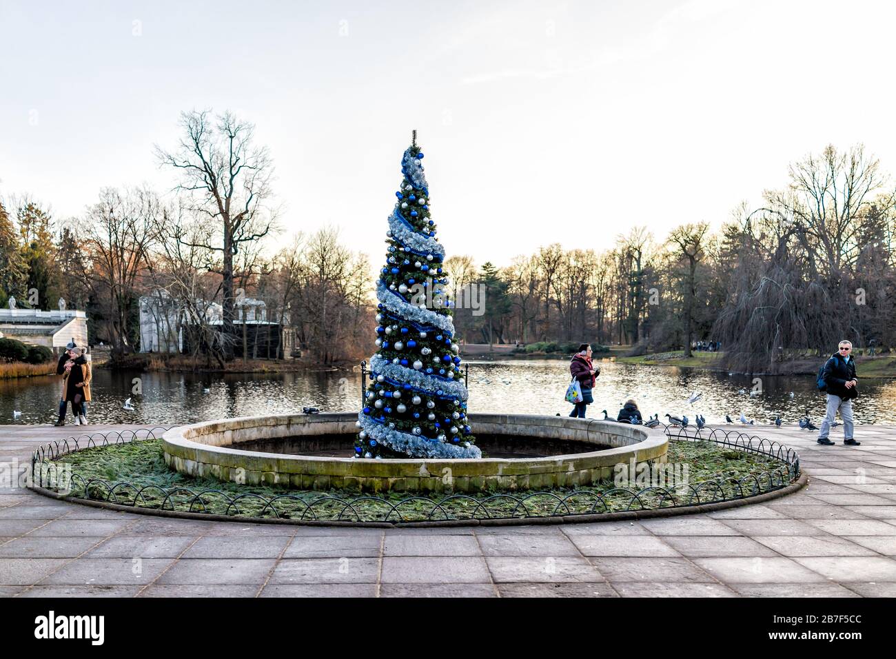 Warschau, Polen - 20. Dezember 2019: Menschen, die an dekorierten Weihnachtsbäumen spazieren und Enten am See am Warszawa Lazienki oder am Royal Baths Park at Stockfoto