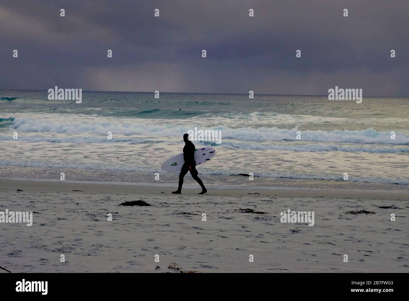 Monterey, Kalifornien, USA. März 2020. Ein einsamer Surfer geht auf den Ozean hinaus, während sich Sturmwolken über dem Pazifik vor Monterey, Kalifornien, sammeln, um noch mehr zu dämpfen, die Stimmung eines depressiven Staates, der von der COVID-19-Virus-Pandemie bedroht ist. Kredit: Motofoto/Alamy Live News Stockfoto