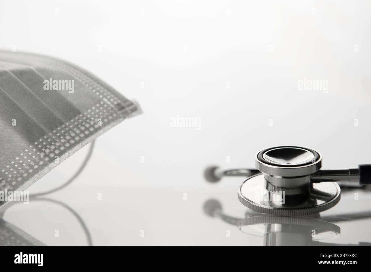 Medizinisches Stethoskop und weiße Maske zur Diagnose von Viruserkrankungen auf gesundheitlichem weißem Hintergrund Stockfoto
