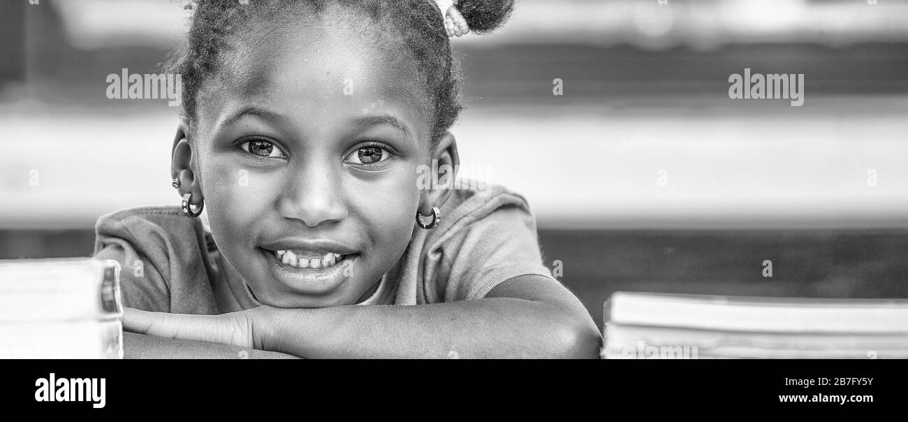 Glückliches afrikanisches Mädchen in der Schule an ihrem Schreibtisch. Stockfoto