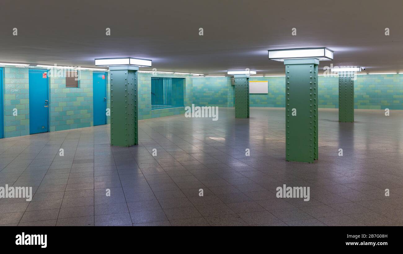 Blick in die Eingangshalle des U-Bahnhofs Alexanderplatz. Leere Halle mit grünen Fliesen, quadratischen Säulen und Neonlicht. Minimalistisches Design. Stockfoto