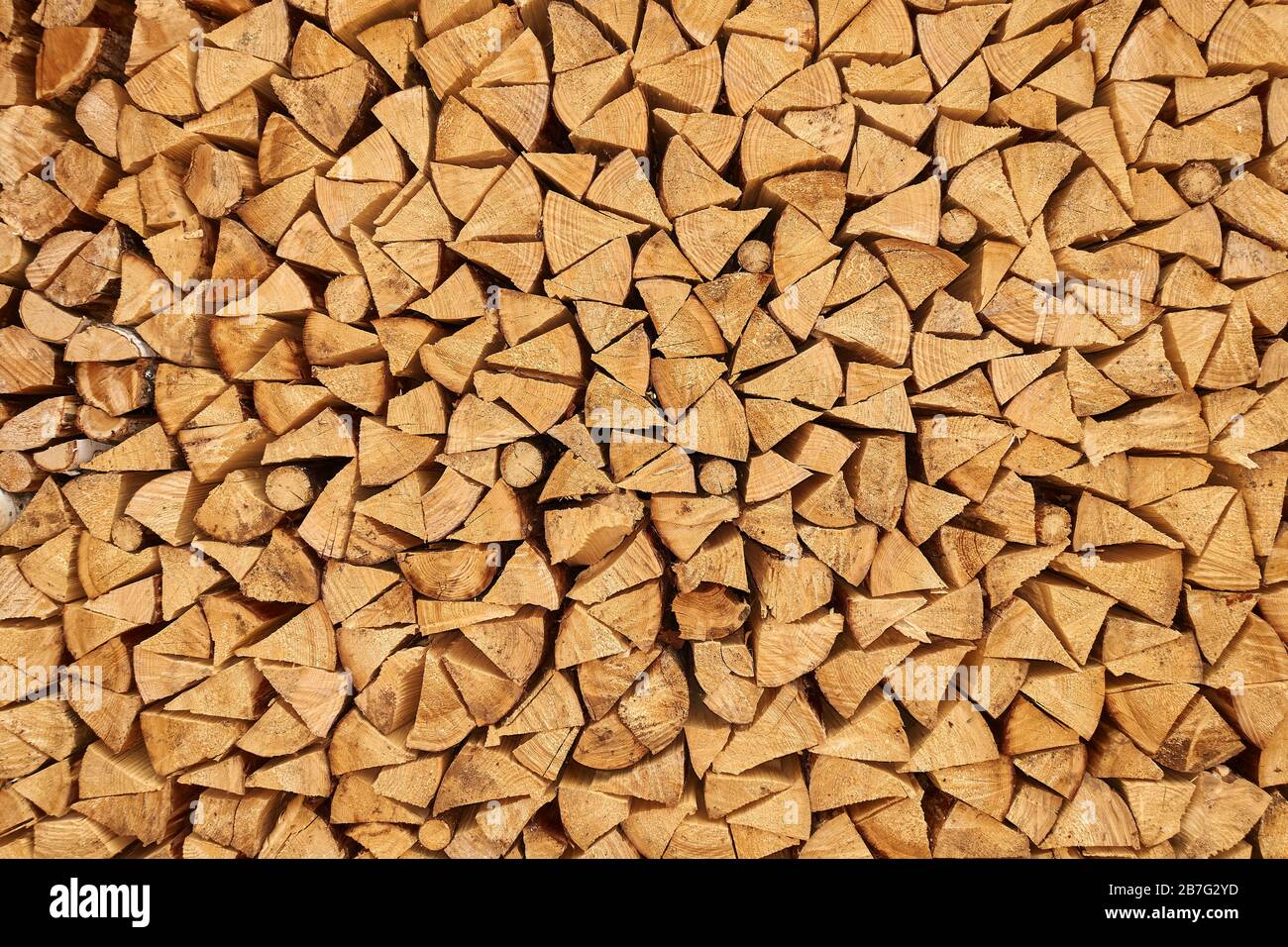 Hintergrundbild von gestapelten, trocken gehackten Holzstämmen, die für Brennholz verwendet werden. Stapel von Holzstämmen, die im Kamin verwendet werden können. Alternative Erwärmungsmethode. Stockfoto