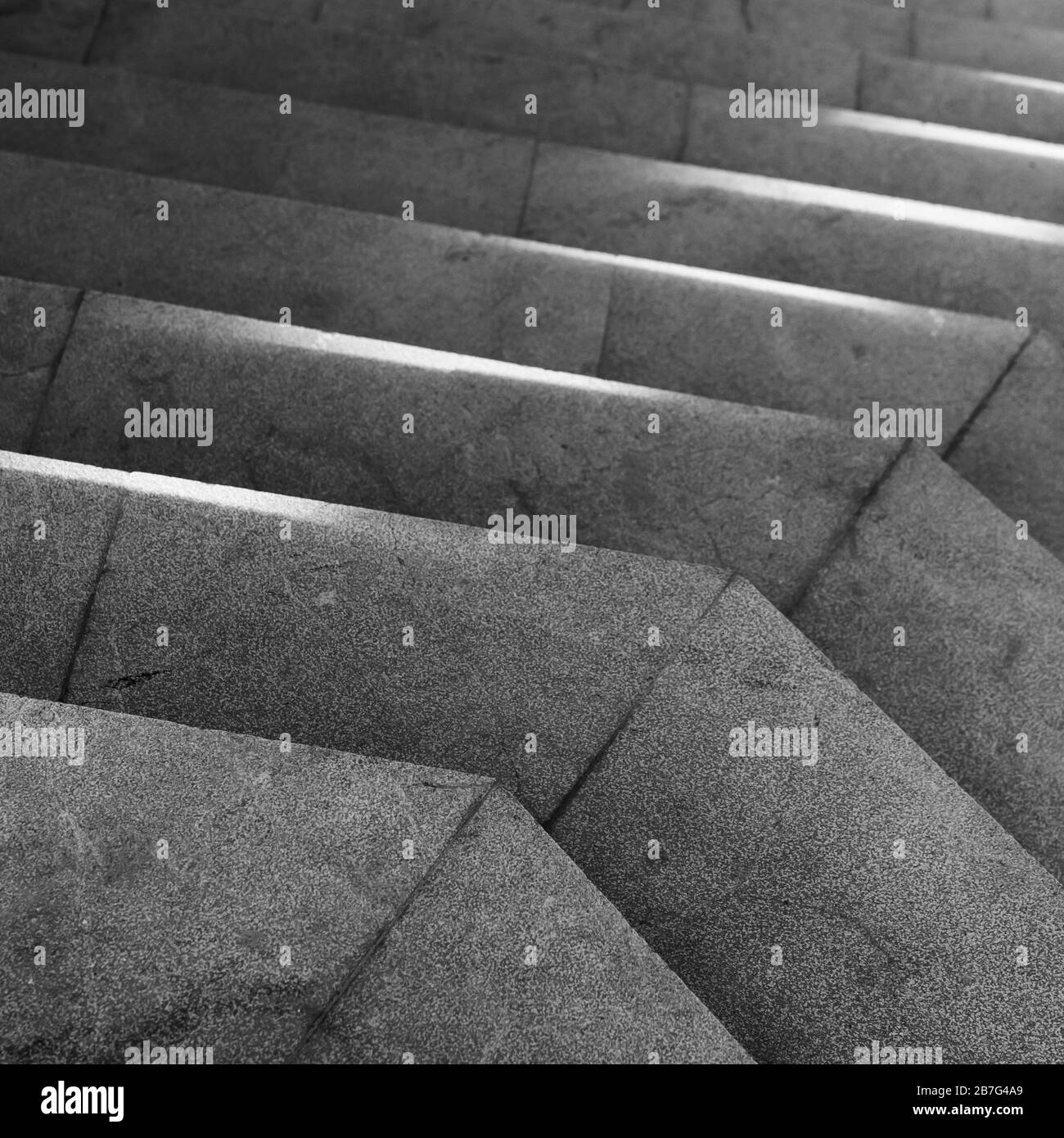 Leere dunkelgraue Steintreppe mit Sonnenlicht darauf. Abstrakte Architektur quadratisches Schwarz-Weiß-Hintergrundfoto Stockfoto
