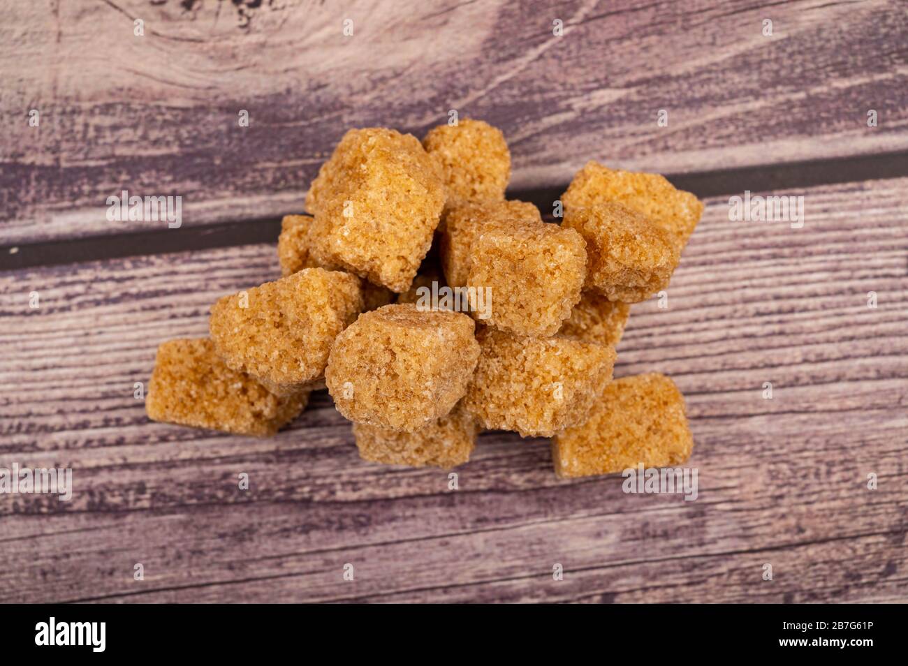 Ein kleiner Haufen brauner Zuckerklumpen auf Holzgrund. Nahaufnahme Stockfoto