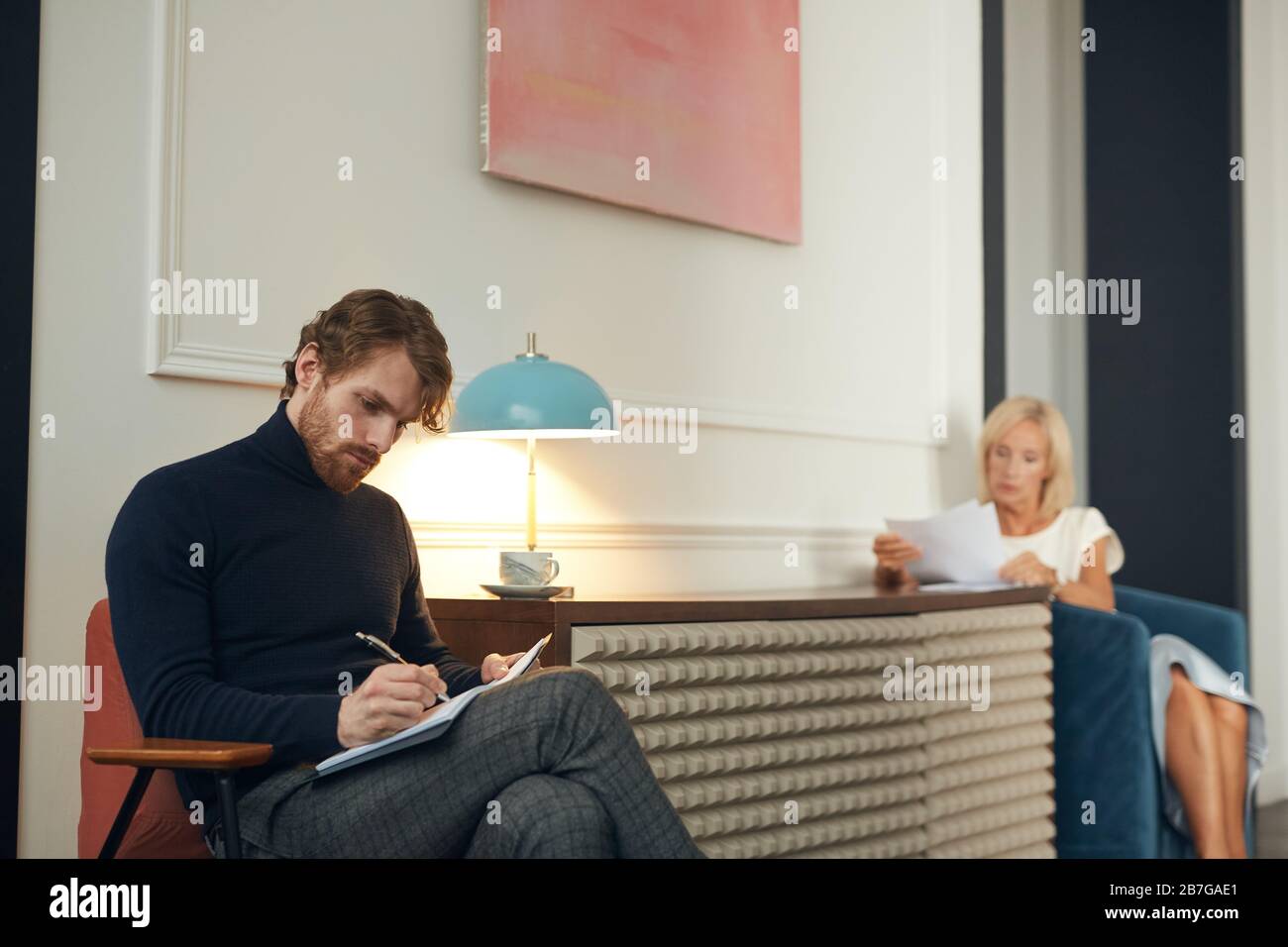 Porträt eines eleganten Mannes und einer Frau, die mit Geschäftsdokumenten im eleganten Interieur arbeiten, Kopienraum Stockfoto