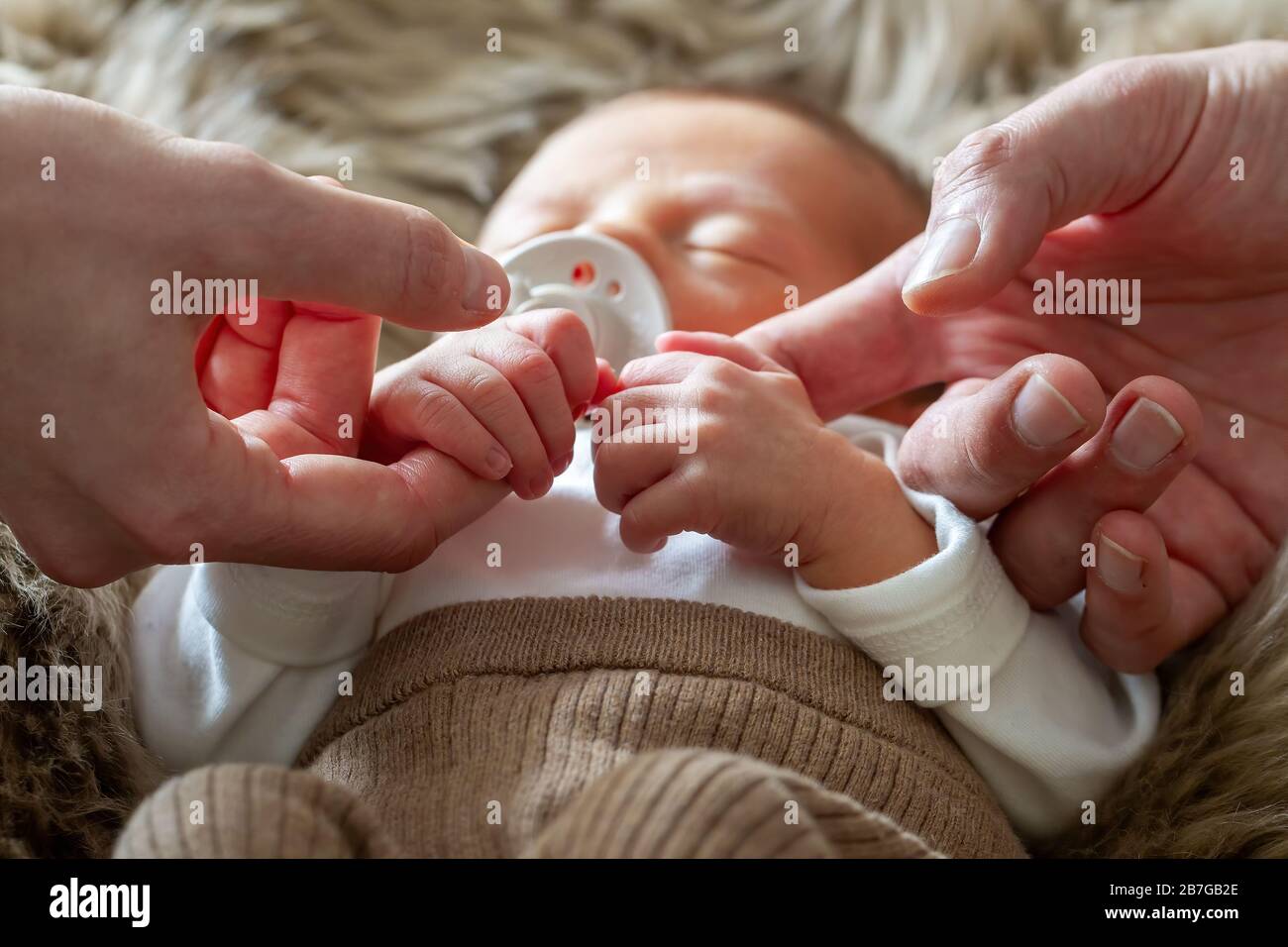 Eltern, die die Hände ihres neugeborenen Babys halten (eine Woche alt) Stockfoto