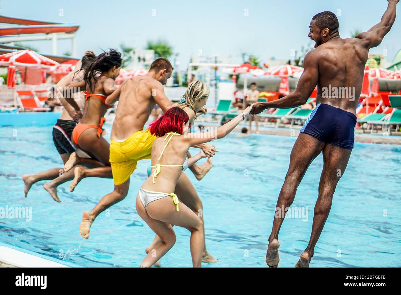 Junge Leute, die glücklich aussehen, während sie gemeinsam in das Schwimmbad springen - glückliche Freunde, die Sommerurlaube im Aquapark haben - Urlaub und Urlaub Stockfoto