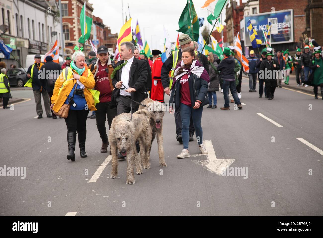 St. Patrick's Day Parade in Manchester, Großbritannien. Cllr John Flanagan, entre, hält die Leads für seine Hunde Finnan und Oisins Stockfoto