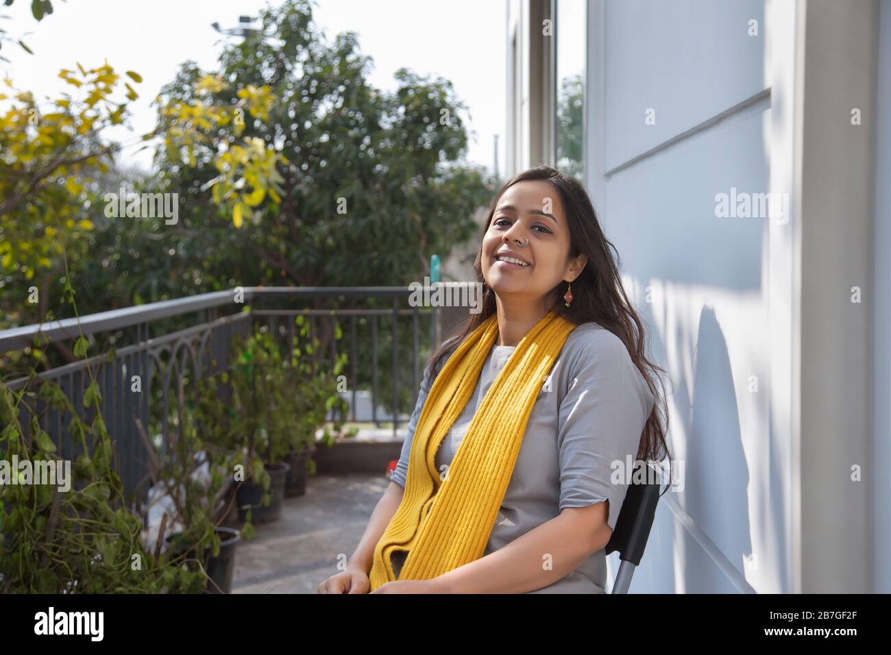 Schöne Frau, die auf ihrem Balkon unter der Sonne sitzt. Stockfoto